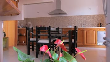 Una cocina con armarios de madera, salpicadero de azulejos y un comedor con sillas y mesa.