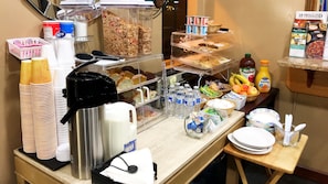 A breakfast bar with various food items, including cereals, pastries, and beverages.