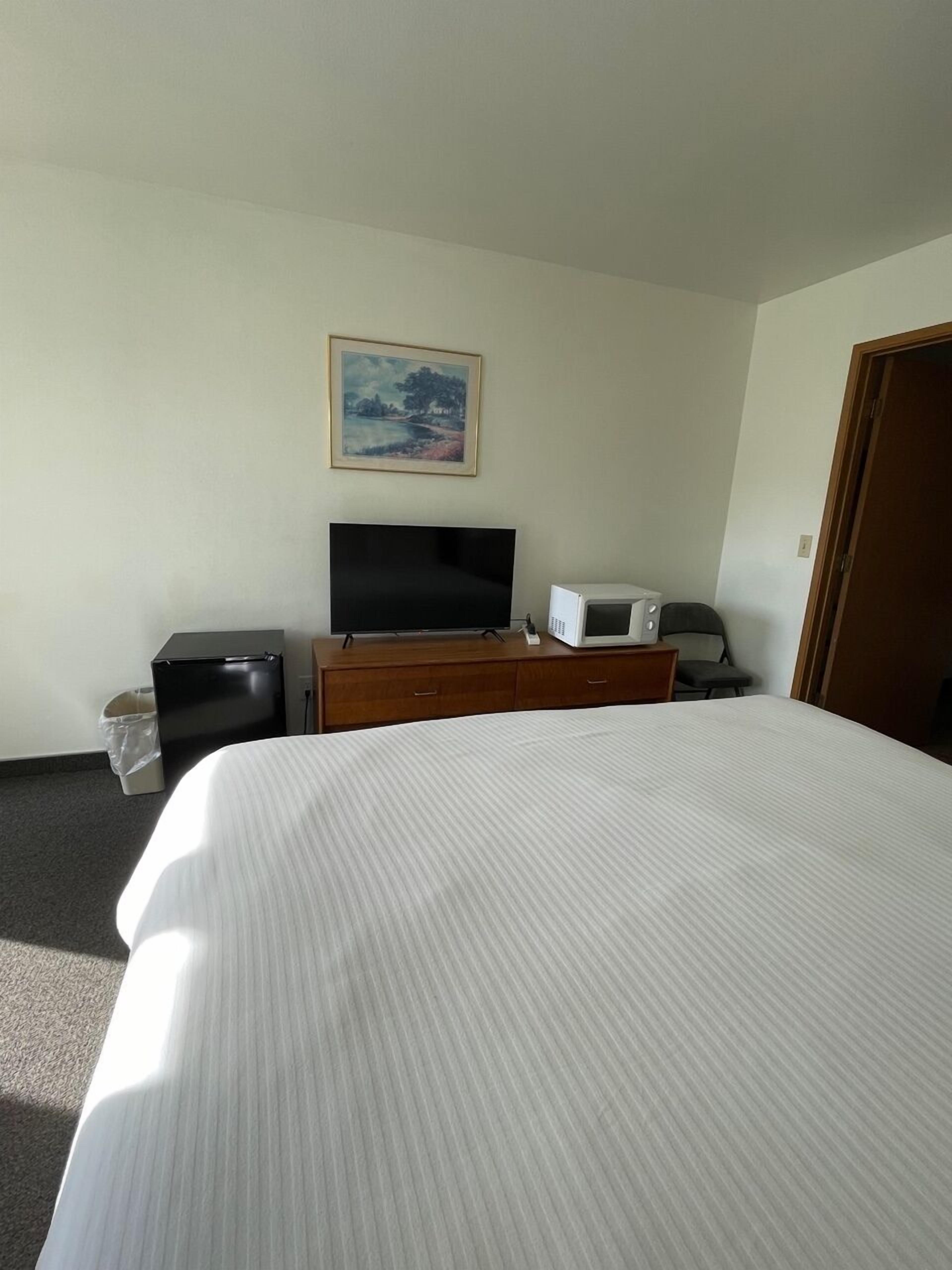 Habitación de hotel con una cama grande, televisión de pantalla plana, microondas y un pequeño escritorio.