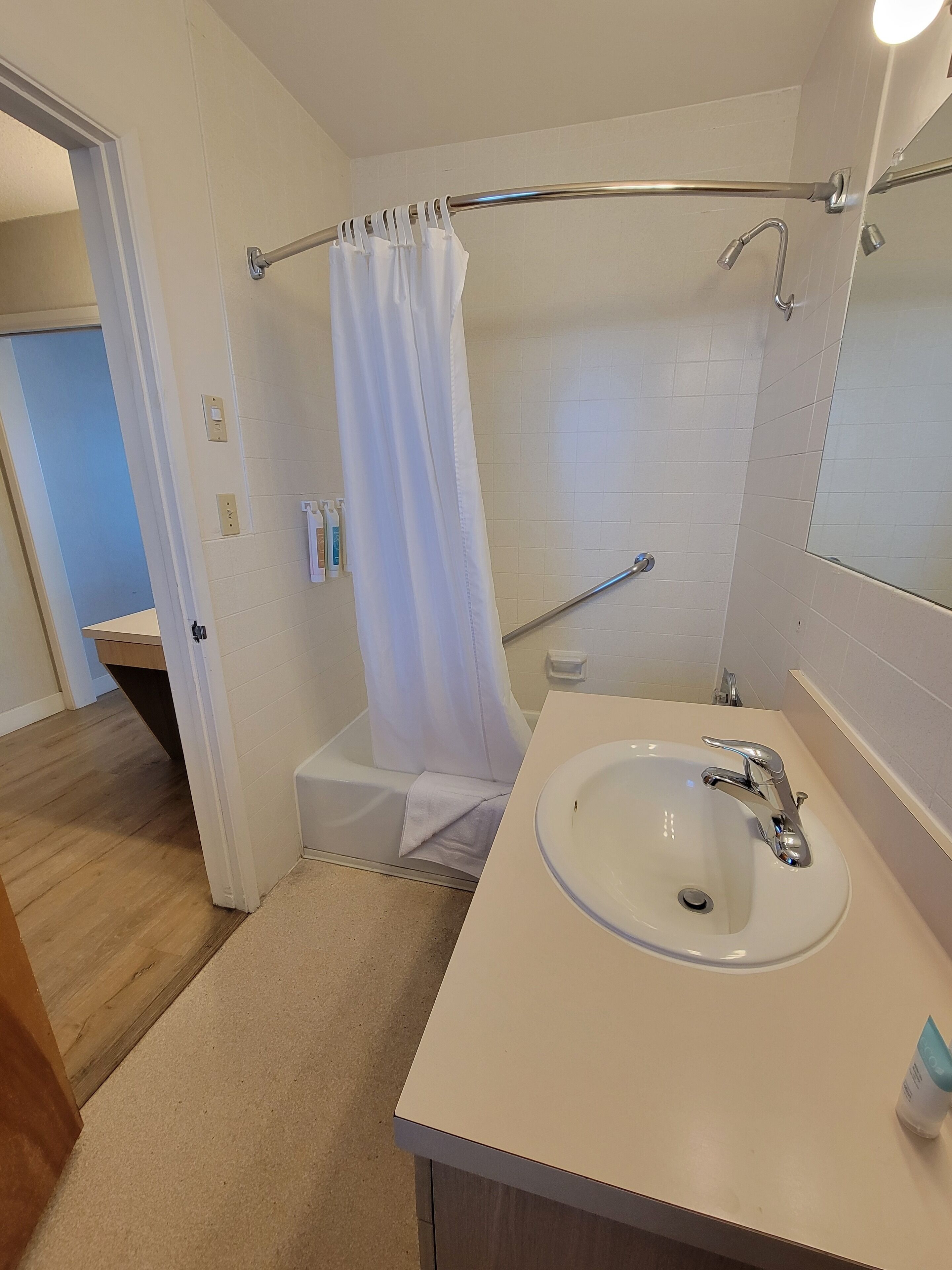 Un baño con lavamanos blanco, cortina de ducha, bañera y espejo.