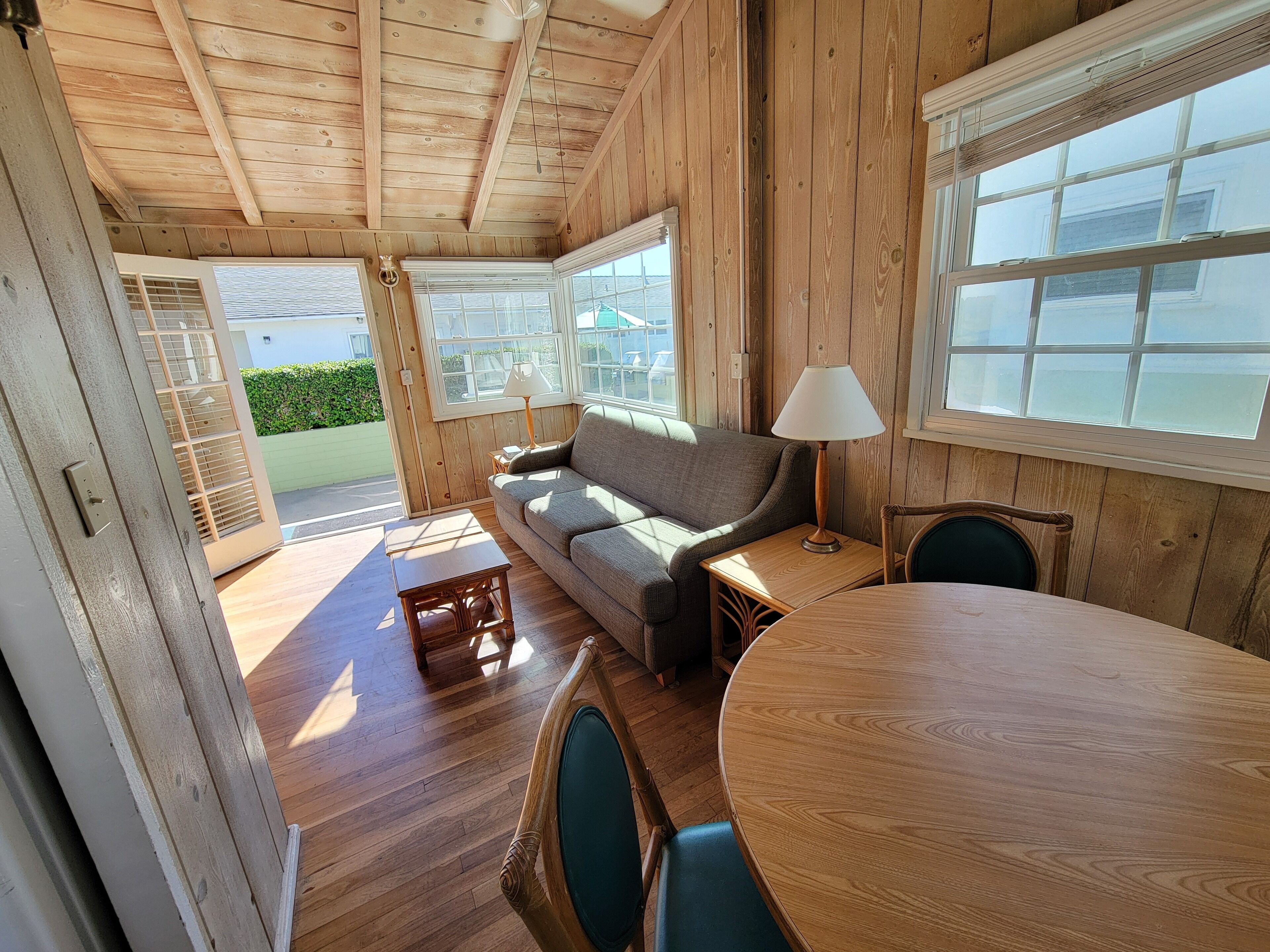 A wooden interior with a sofa, a table, and a lamp.