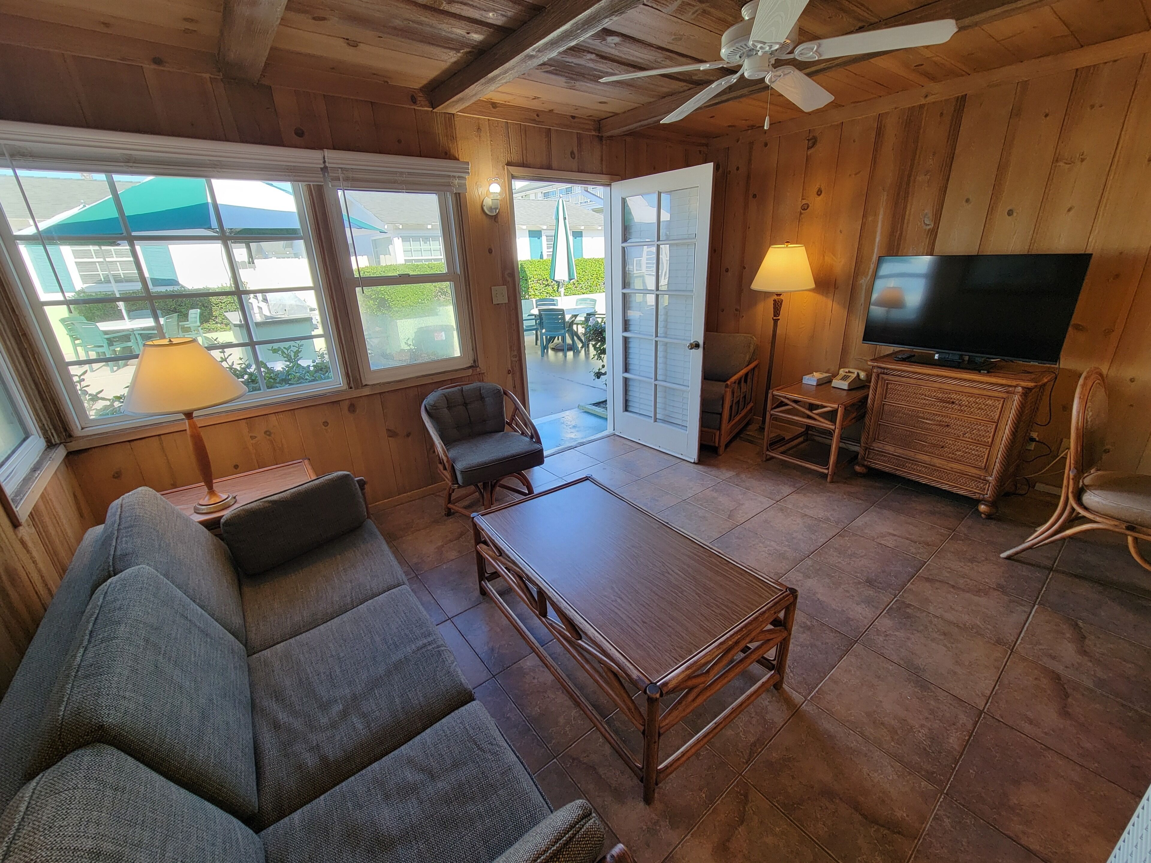 A cozy living room with a sofa, a wooden coffee table, a television, and a wicker side table.