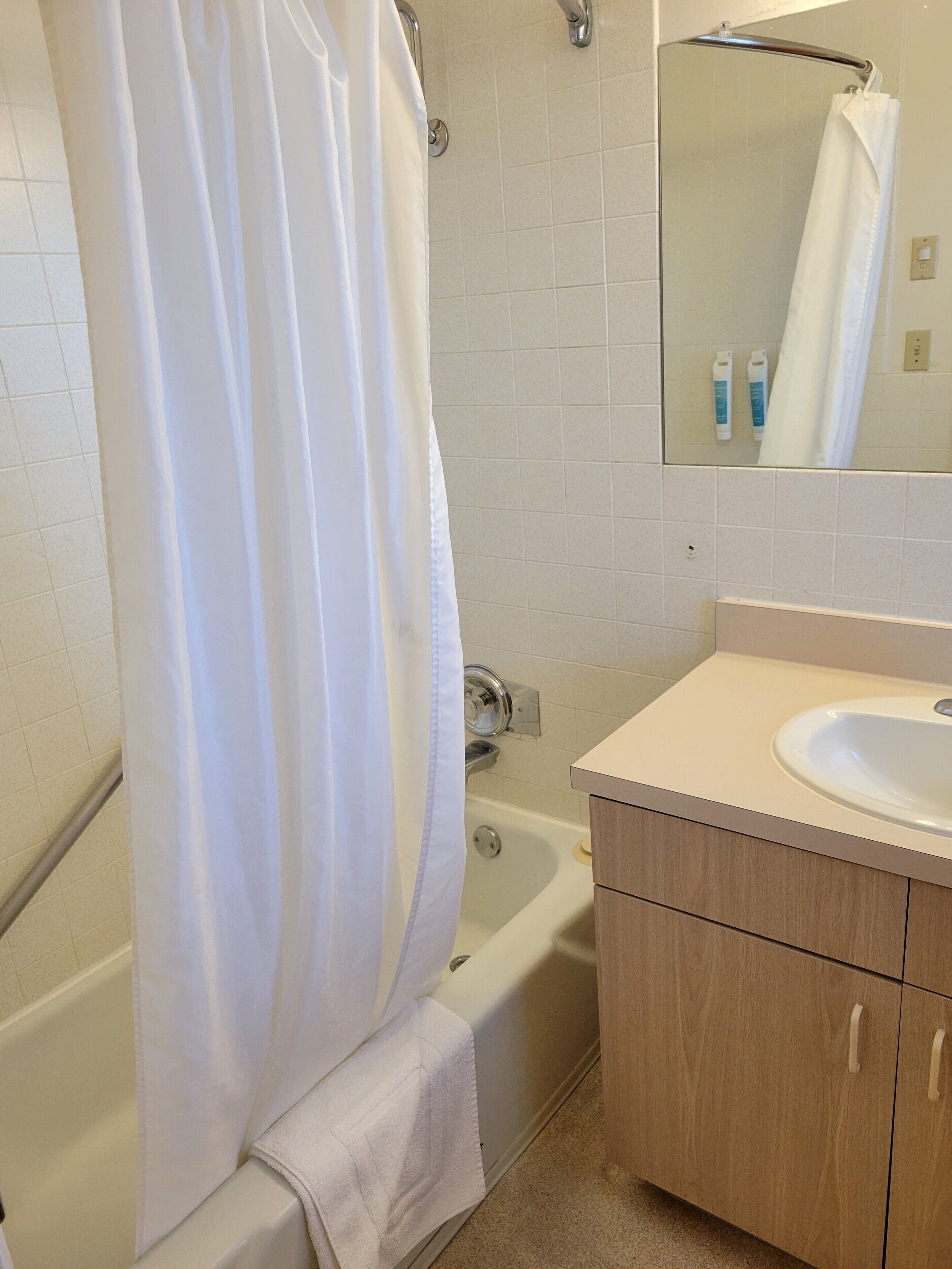 A bathroom with a bathtub, a sink, and a mirror.