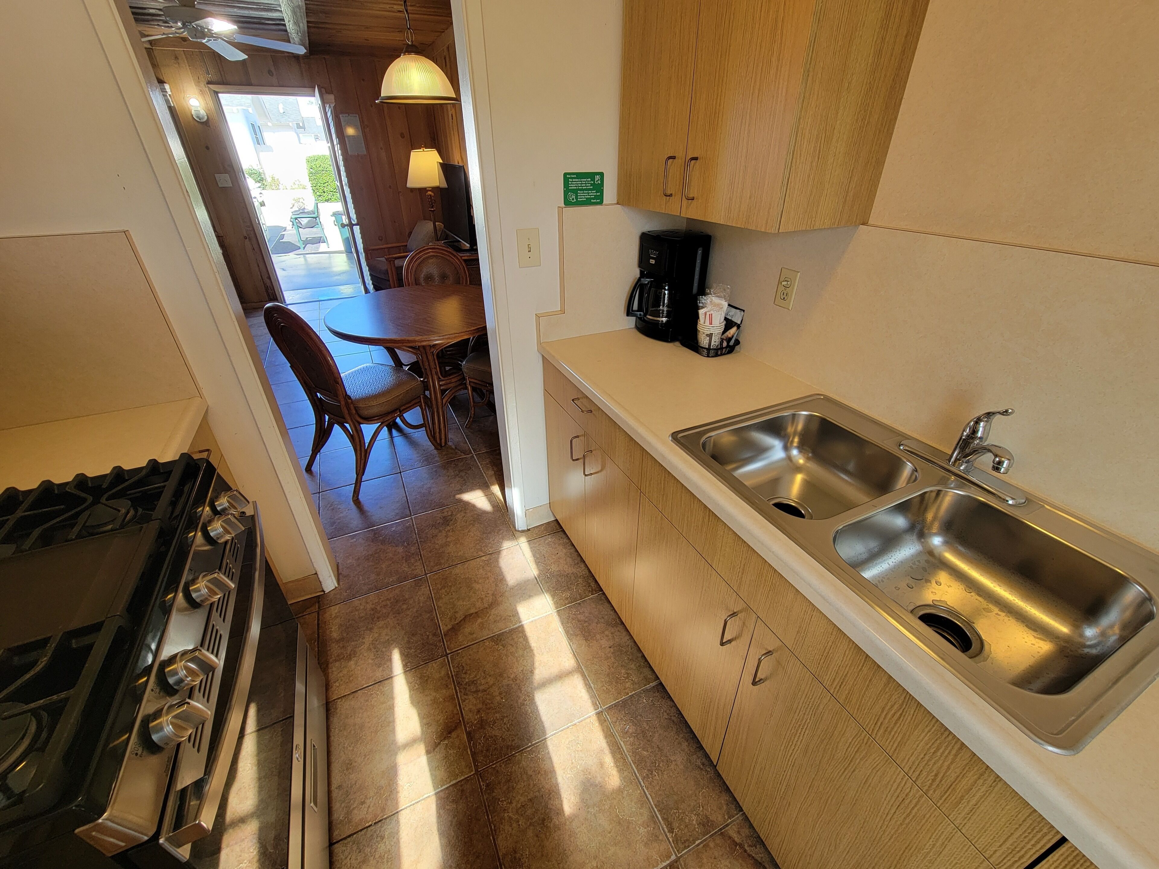 Una cocina con estufa, lavamanos y comedor con sillas y una mesa.
