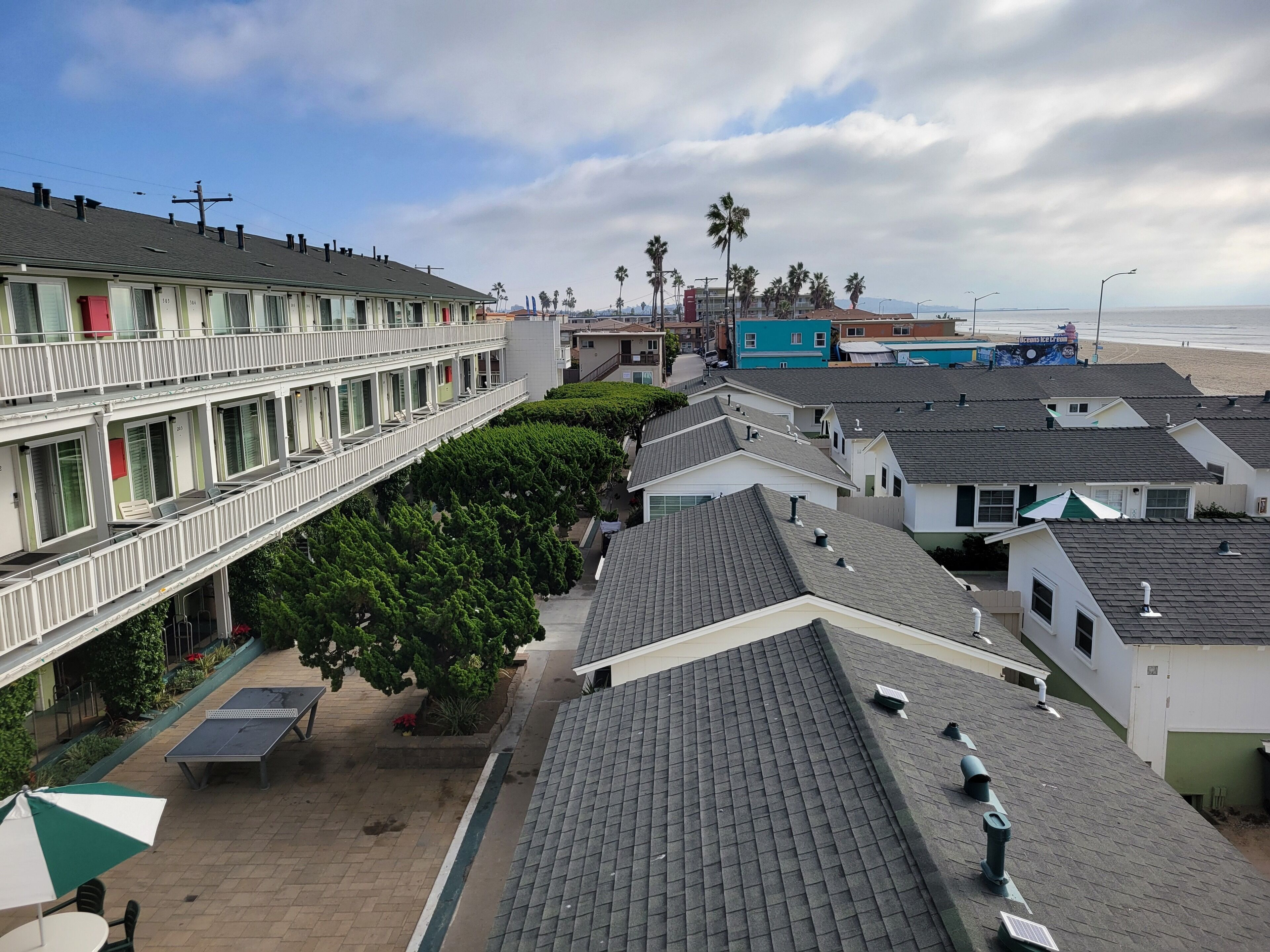 A multi-story hotel with balconies, a rooftop garden, and a view of the beach.