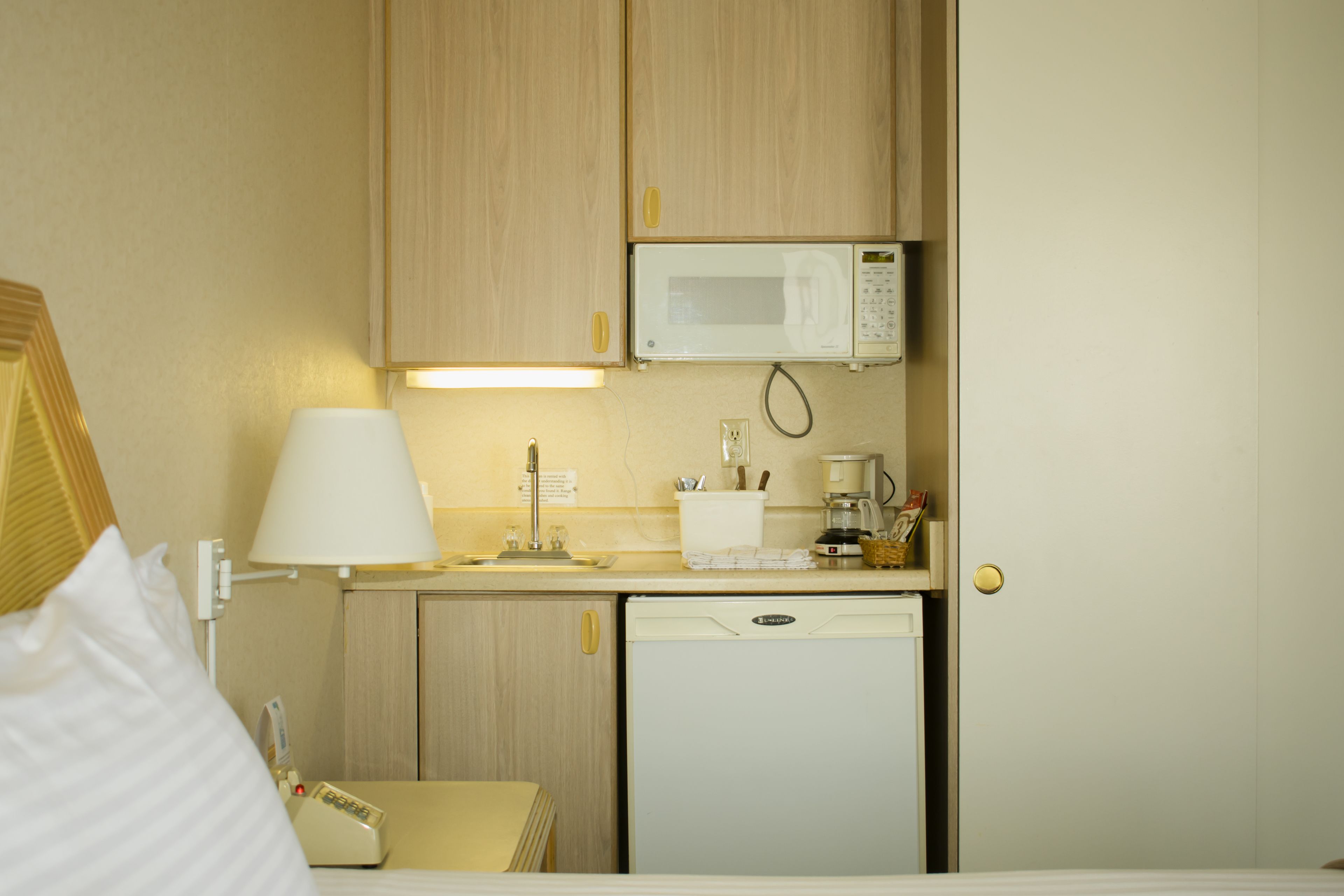 A compact hotel kitchenette with a microwave, coffee maker, and a small refrigerator.