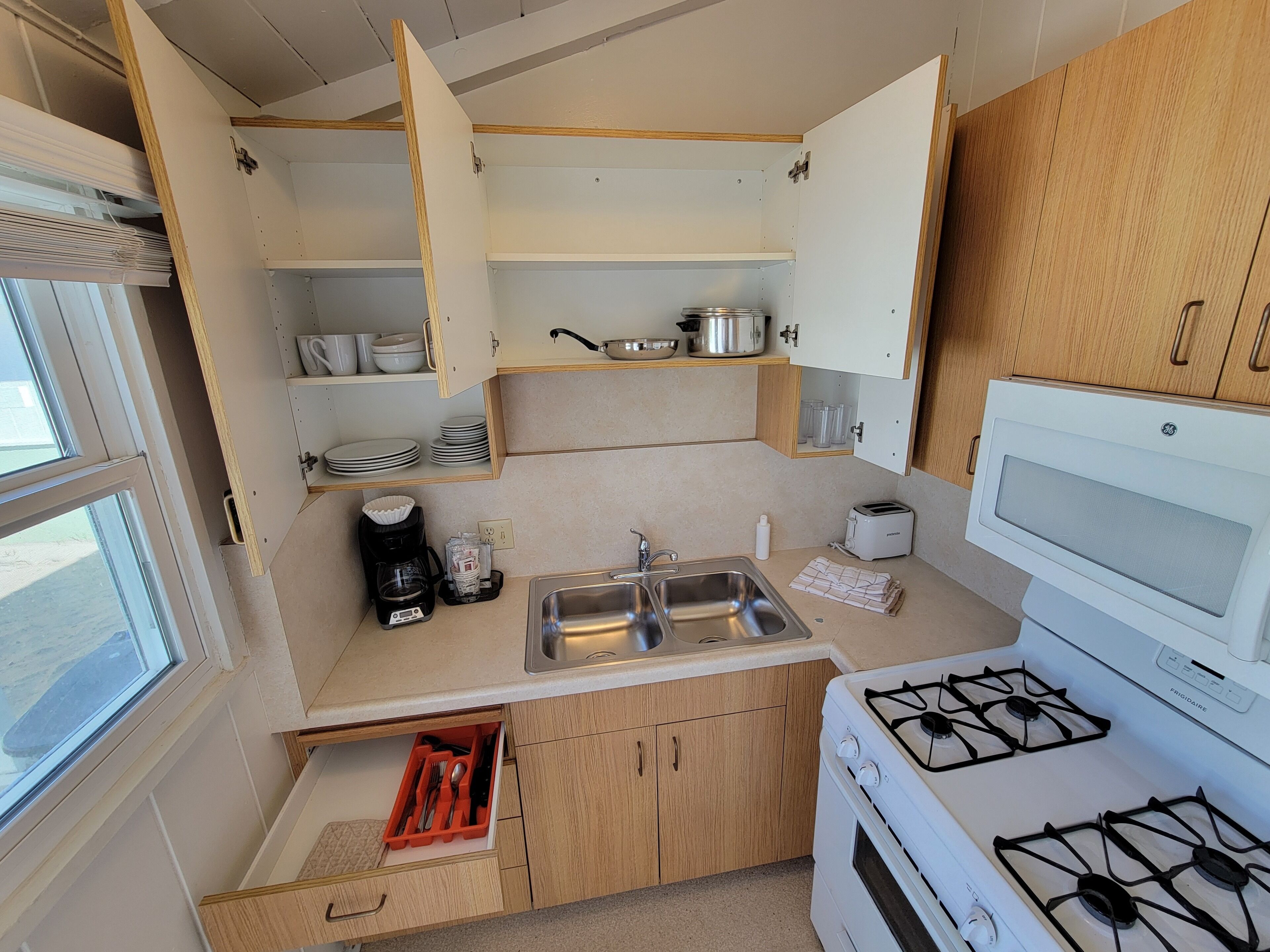 A compact kitchen with a gas stove, a sink, and wooden cabinets.