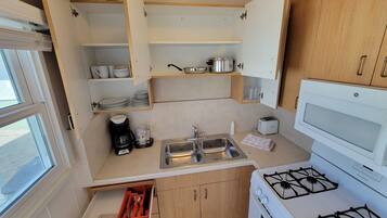 A compact kitchen with a gas stove, a sink, and wooden cabinets.