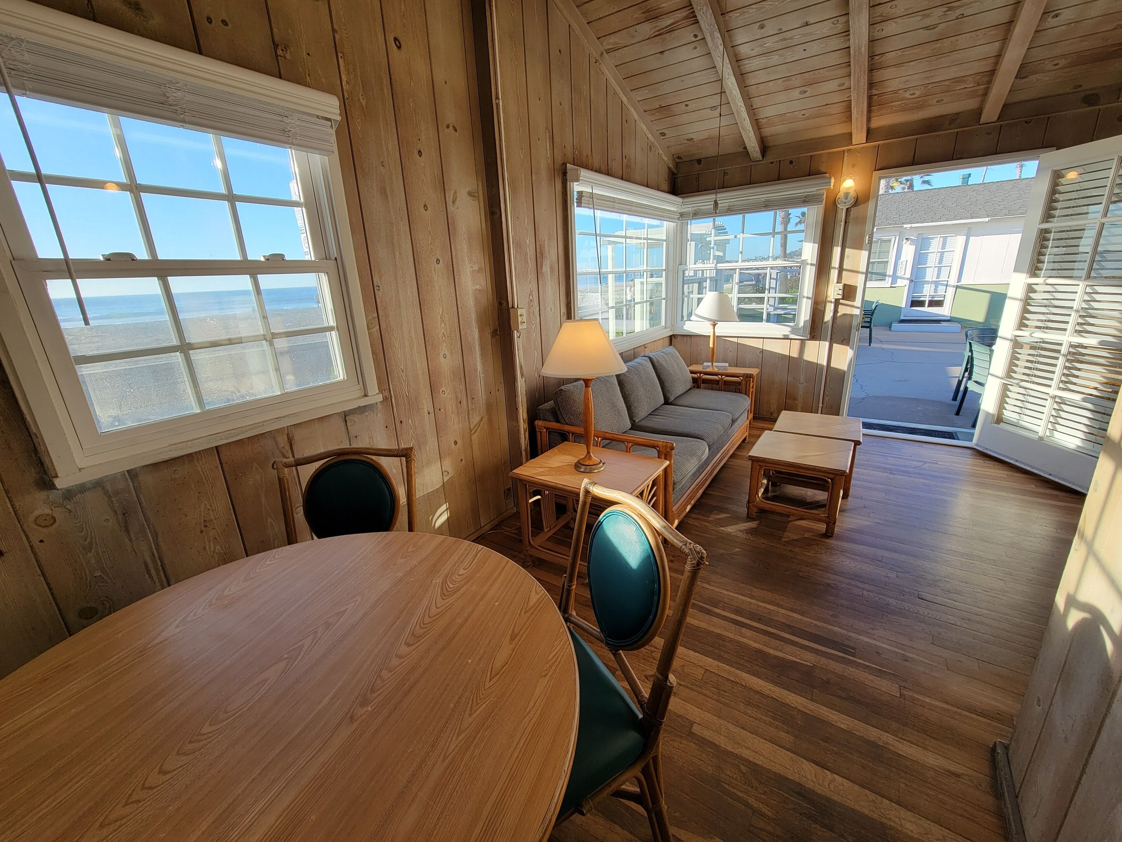 A wooden interior with a round table, chairs, a sofa, and a lamp.