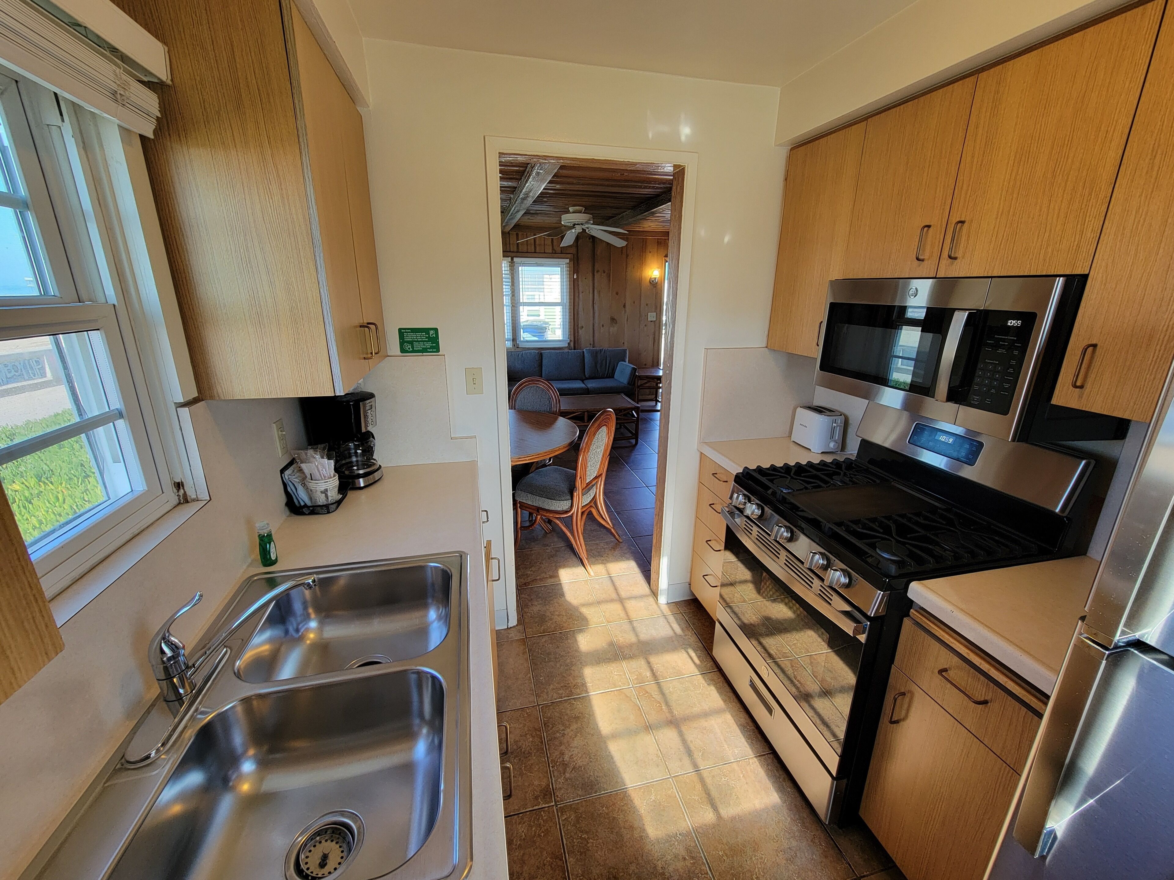 A compact kitchen with stainless steel appliances, a sink, and wooden cabinets.