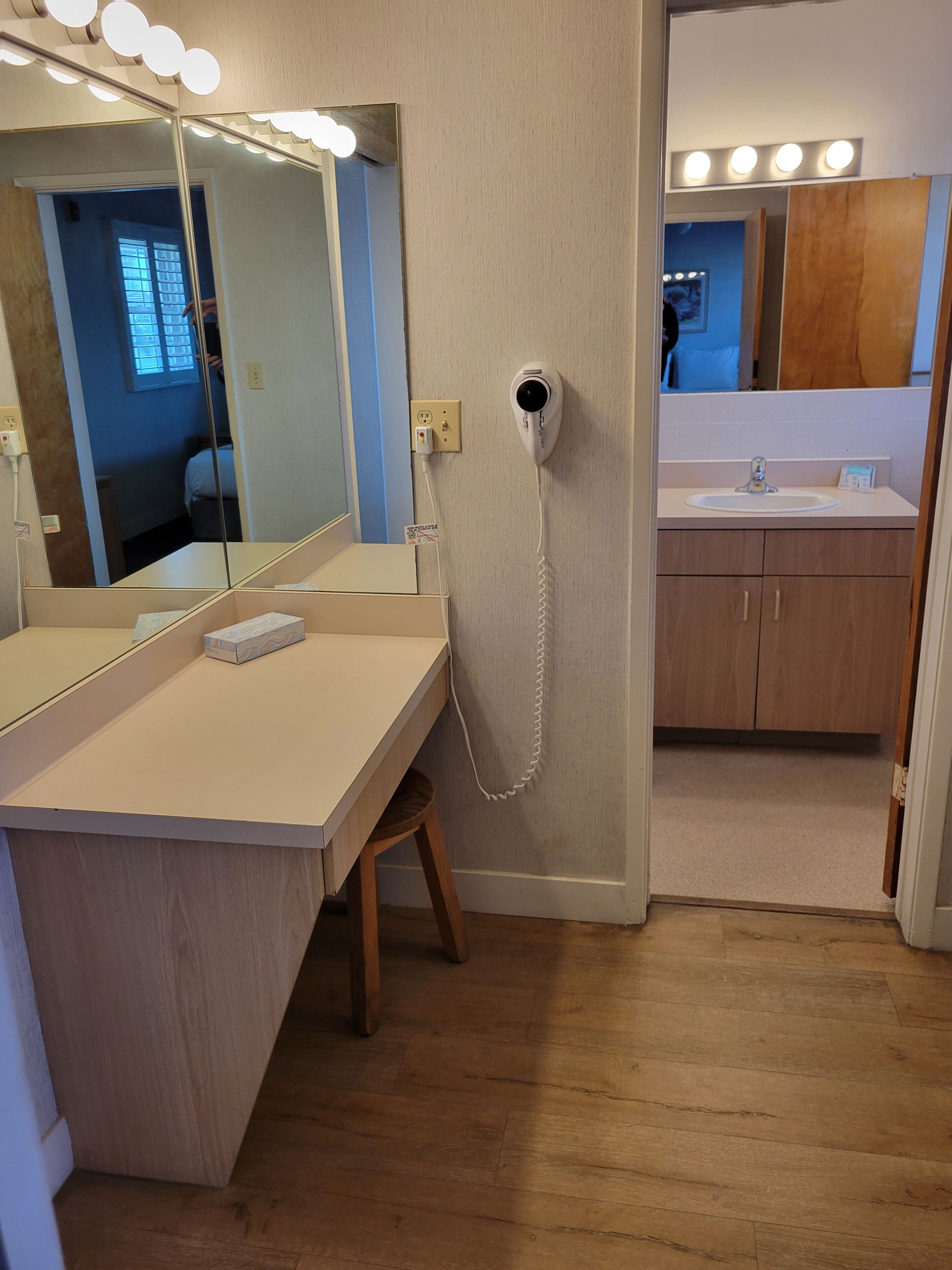 A bathroom with a vanity, mirror, and hairdryer.
