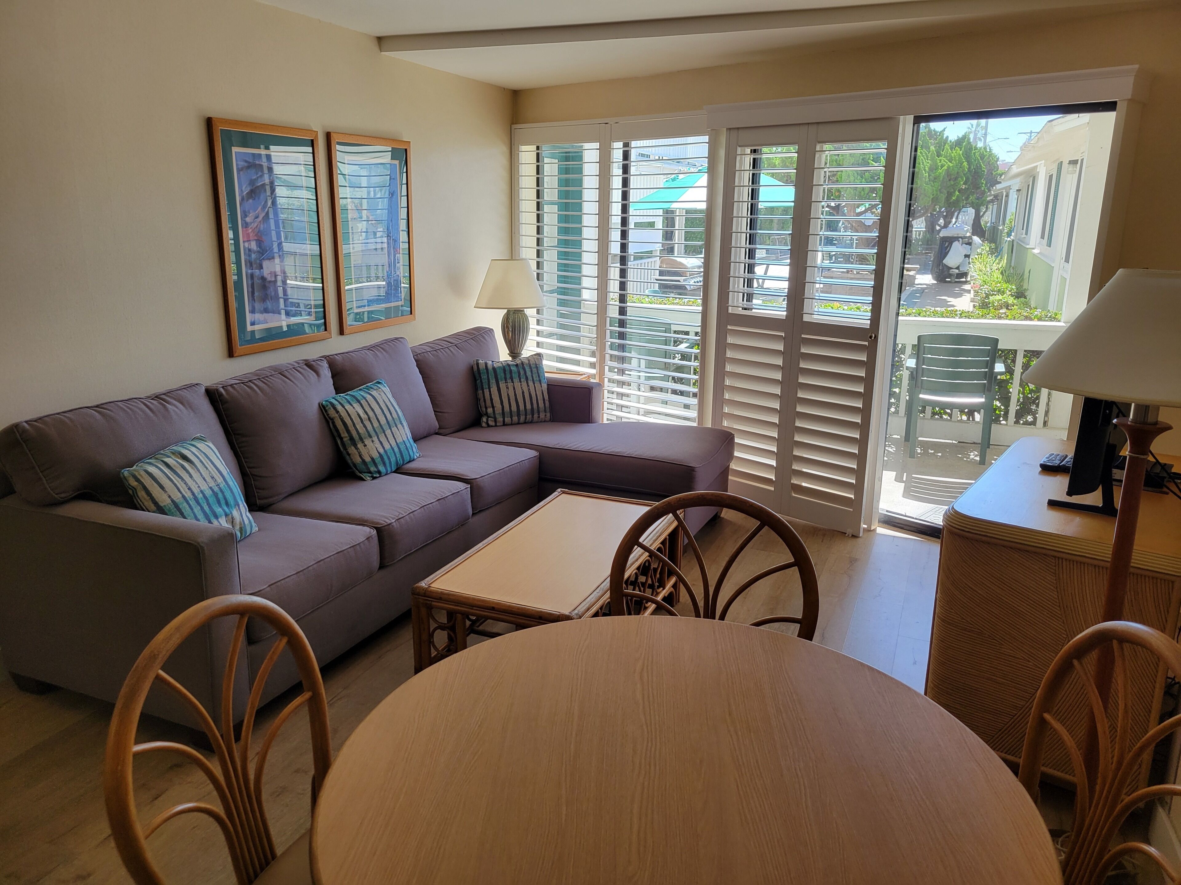 Un salon comprenant un canapé, deux fauteuils, une petite table et un balcon avec des portes coulissantes.