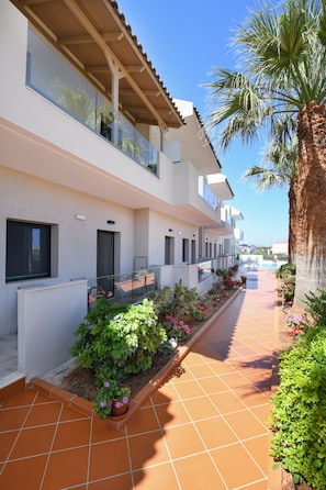 Un edificio moderno con un patio empedrado, un balcón y una palmera.