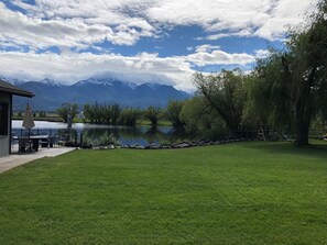 A lakeside property with a patio, a small building, and a view of mountains.