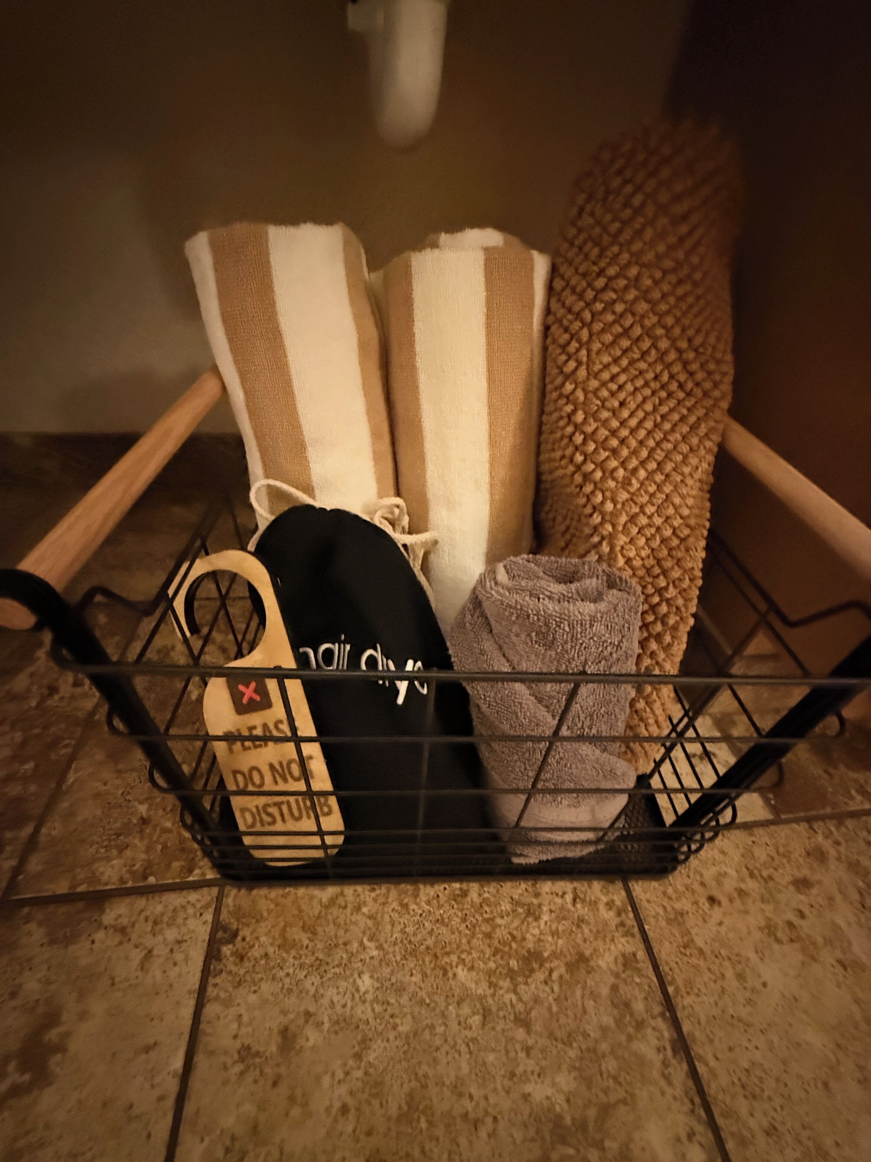 A metal basket containing a towel, a black bag, and a sign with a cross symbol.