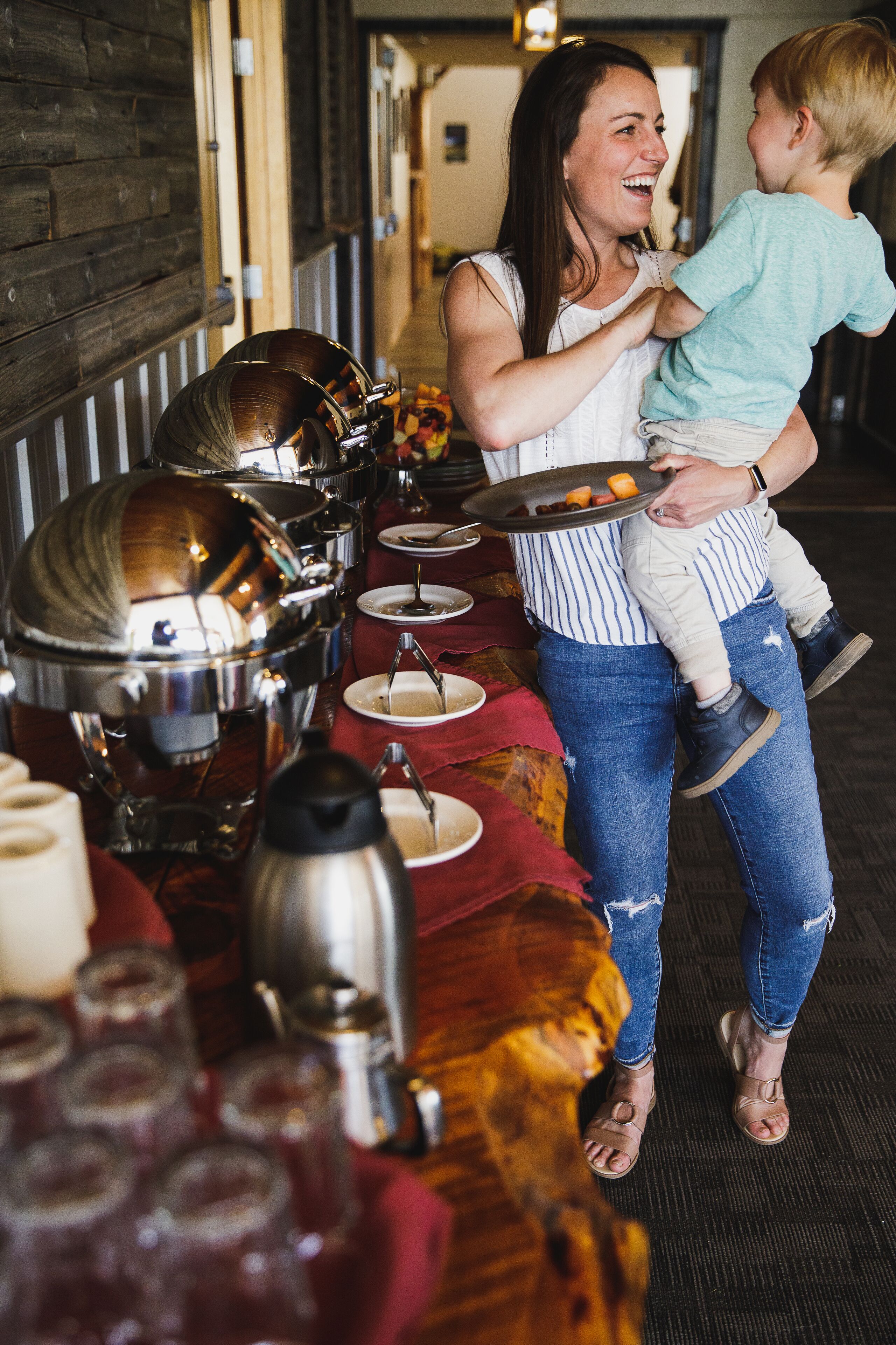 Un buffet avec différents plats disposés dans des récipients et une personne tenant un enfant.
