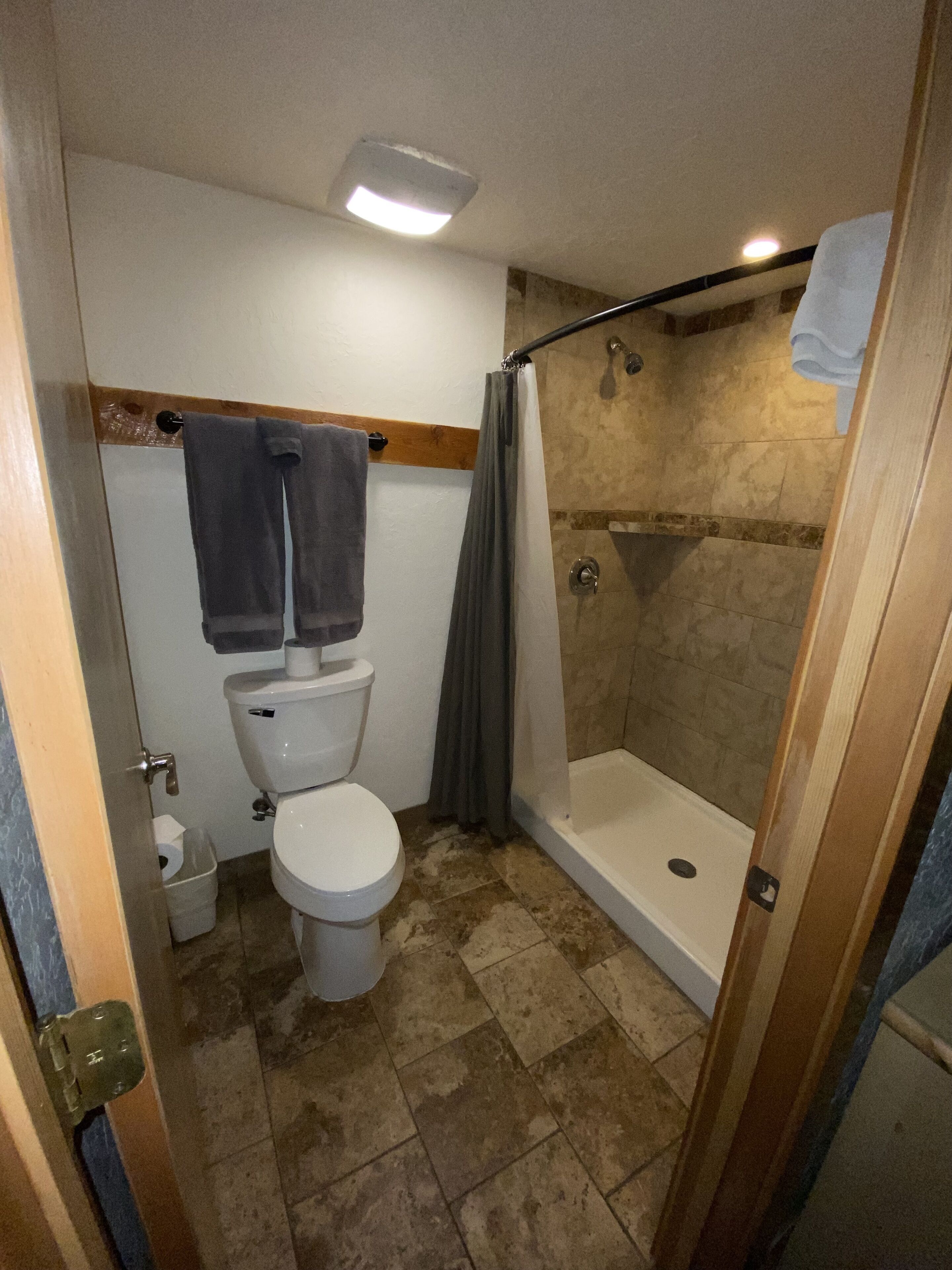 Un baño con inodoro, ducha y barra para toallas.