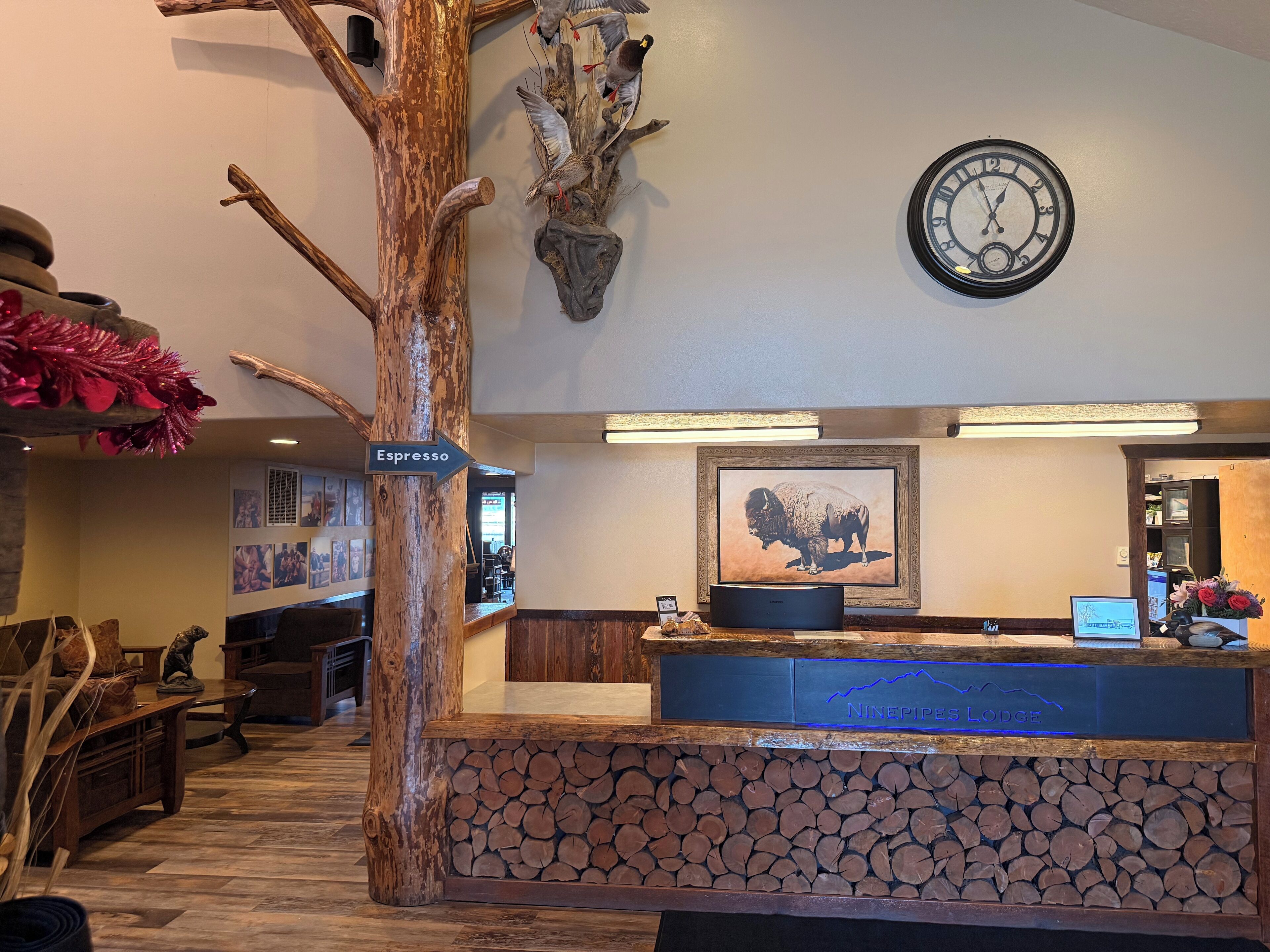 A reception desk with a clock, a sign for Espresso, and a framed buffalo picture.