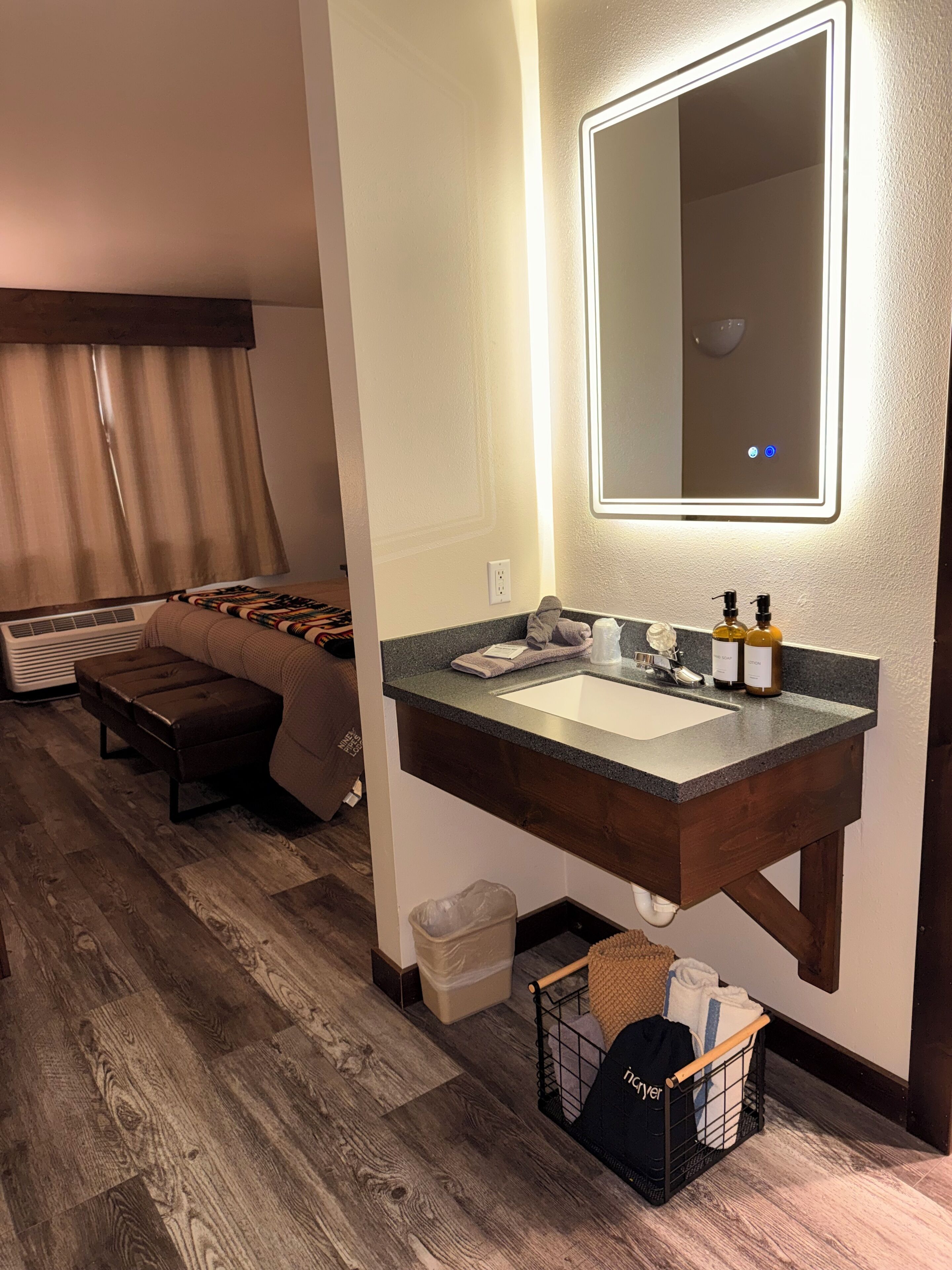 Un baño moderno con un espejo grande, un lavamanos y un banco de madera.