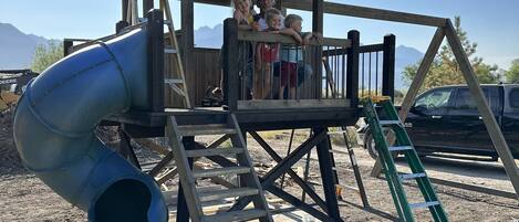 A playground with a slide and a wooden structure.