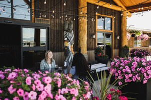 Un espace extérieur aménagé avec des tables et des chaises en bois, entouré de fleurs roses éclatantes.