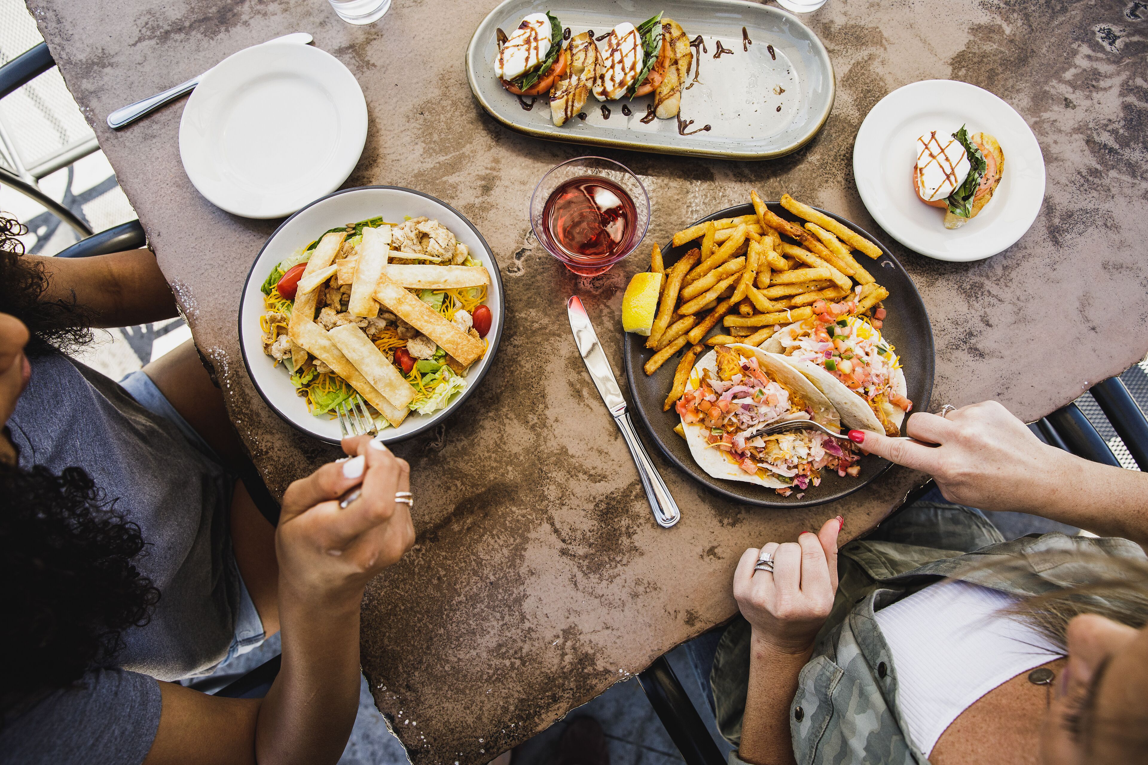 Uma mesa de jantar com diversos pratos, incluindo sanduíches, batatas fritas e uma salada.