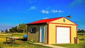 A small, single-story building with a red roof and a white garage door, surrounded by a grassy field and trees. - Gettysburg Inn & Suites (Gettysburg)