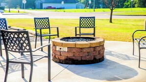 A fire pit with chairs around it, set on a concrete patio. - Gettysburg Inn & Suites (Gettysburg)