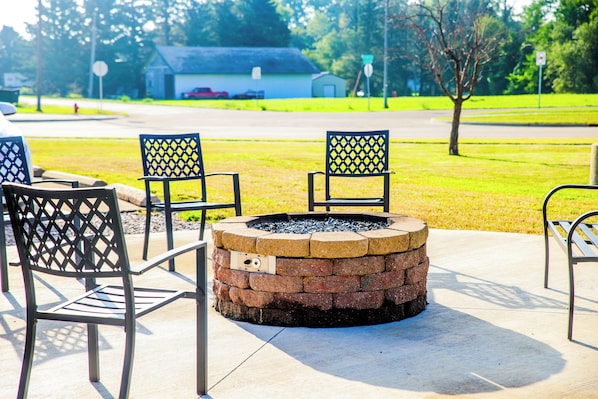 A fire pit with chairs around it, set on a concrete patio.