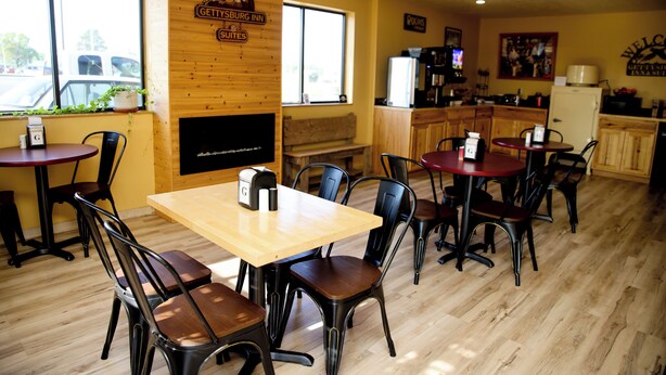 A cozy restaurant with wooden walls and a fireplace, featuring a sign for Gettysburg Inn Suites. - Gettysburg Inn & Suites (Gettysburg)