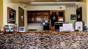 A hotel reception area with a counter displaying various items, a framed picture on the wall, and a sign indicating the room rate. - Gettysburg Inn & Suites (Gettysburg)