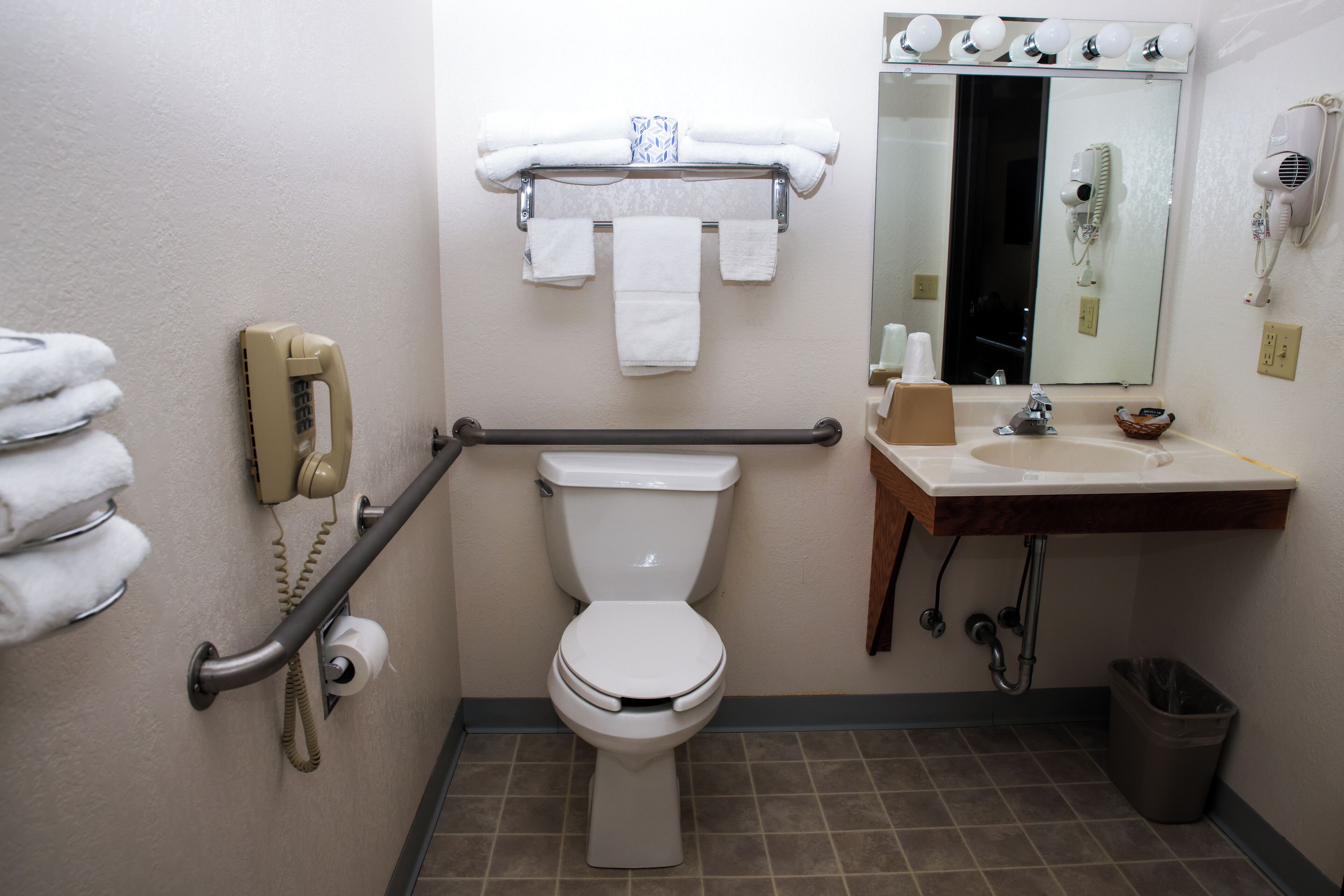 A bathroom with a toilet, a sink, a mirror, and a towel rack.