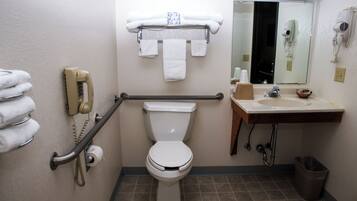 A bathroom with a toilet, a sink, a mirror, and a towel rack.