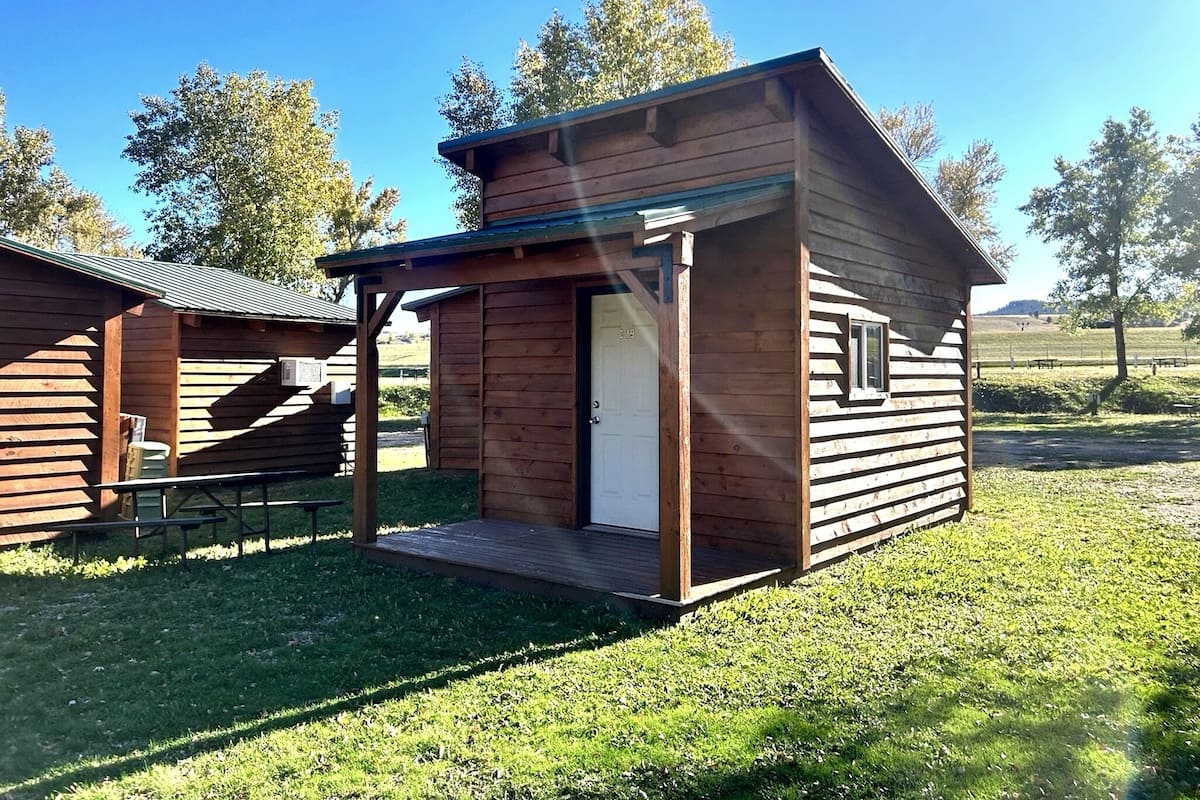A small wooden cabin with a porch, a door, and a window.