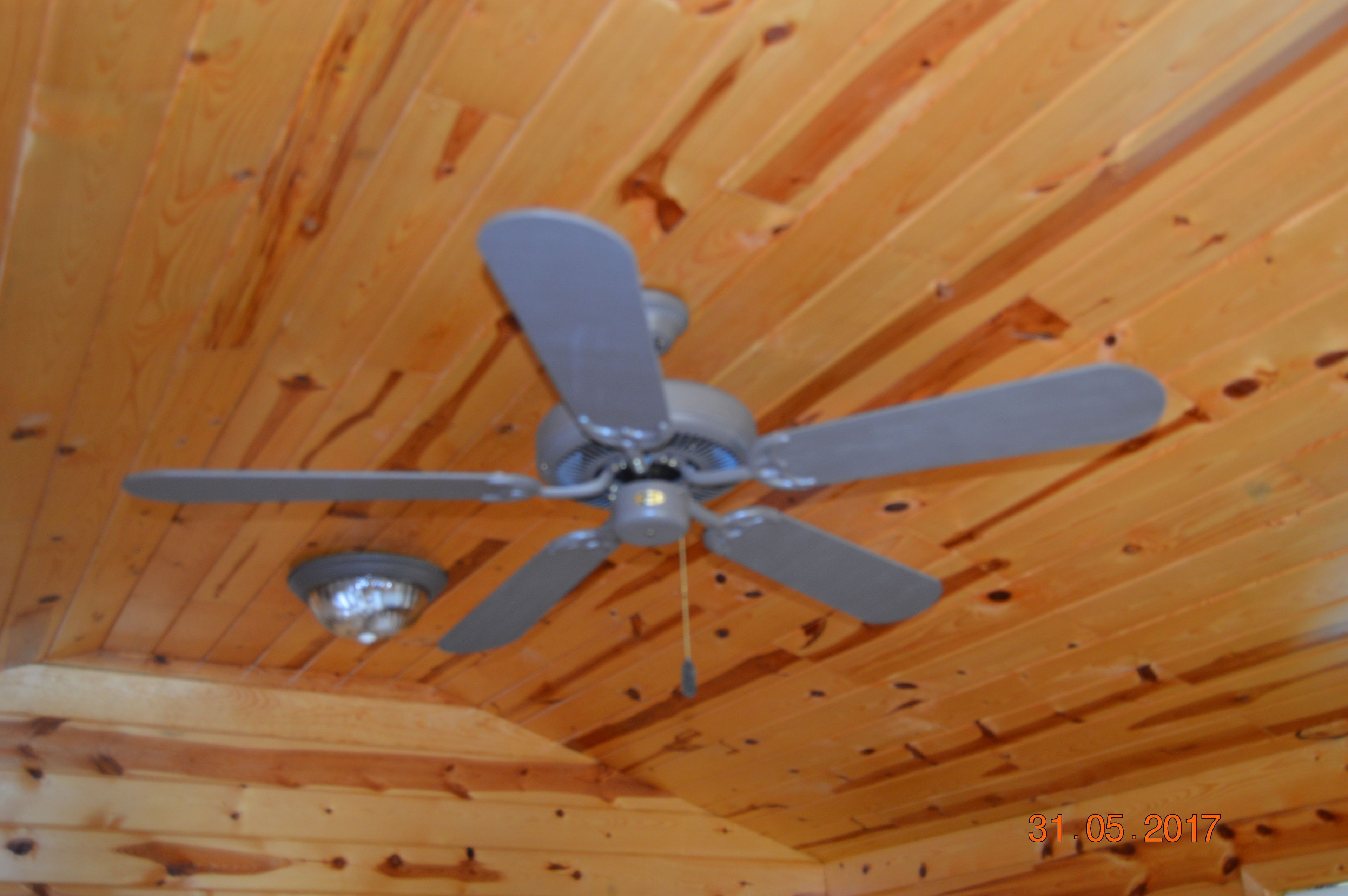 Un ventilador de techo en una habitación de madera.