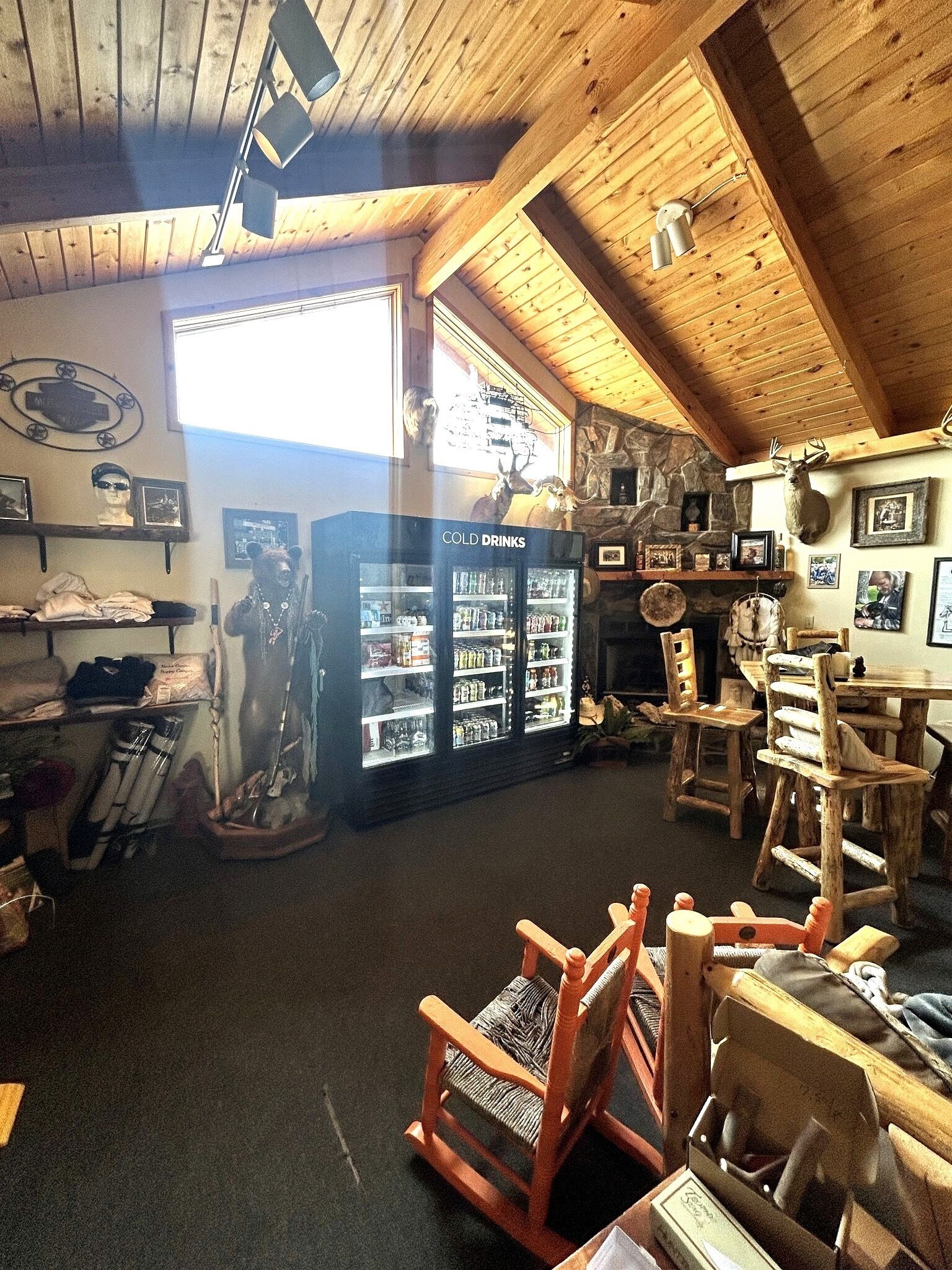 Un intérieur rustique avec des poutres en bois, une cheminée en pierre et un réfrigérateur où sont rangées les « boissons fraîches ».