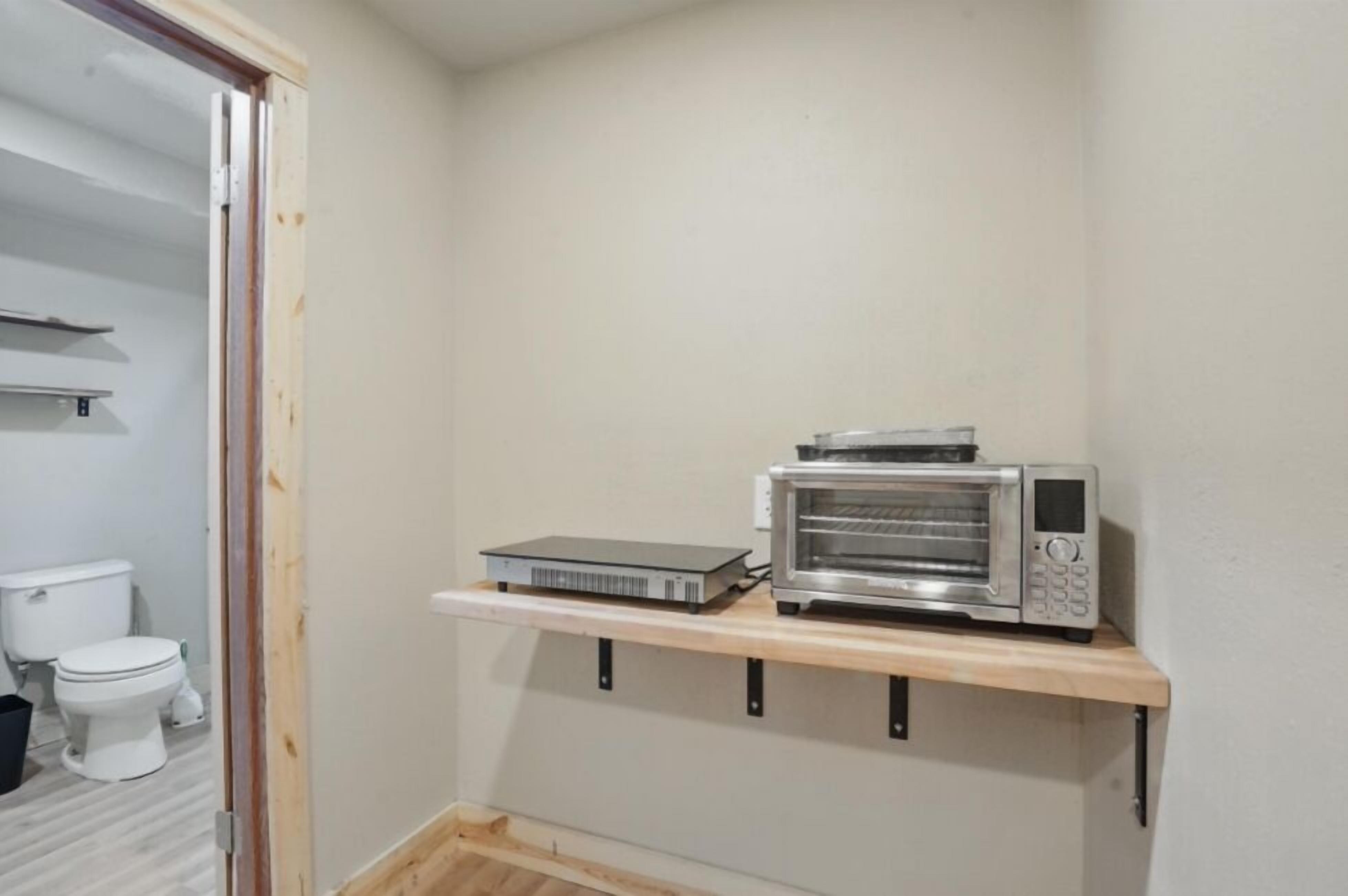 Een kleine kitchenette met een magnetron en een broodrooster op een houten plank.