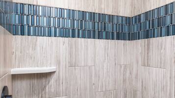Een douchegedeelte met een houten wand, een blauw betegeld plankje en een witte plank.
