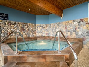 A spa with a capacity of 7 persons, a stone wall, and a wooden ceiling. - Grand Superior Lodge (Two Harbors)