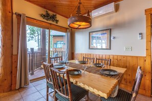A wooden dining table with chairs, a hanging light fixture, and a framed picture on the wall. - Grand Superior Lodge (Two Harbors)