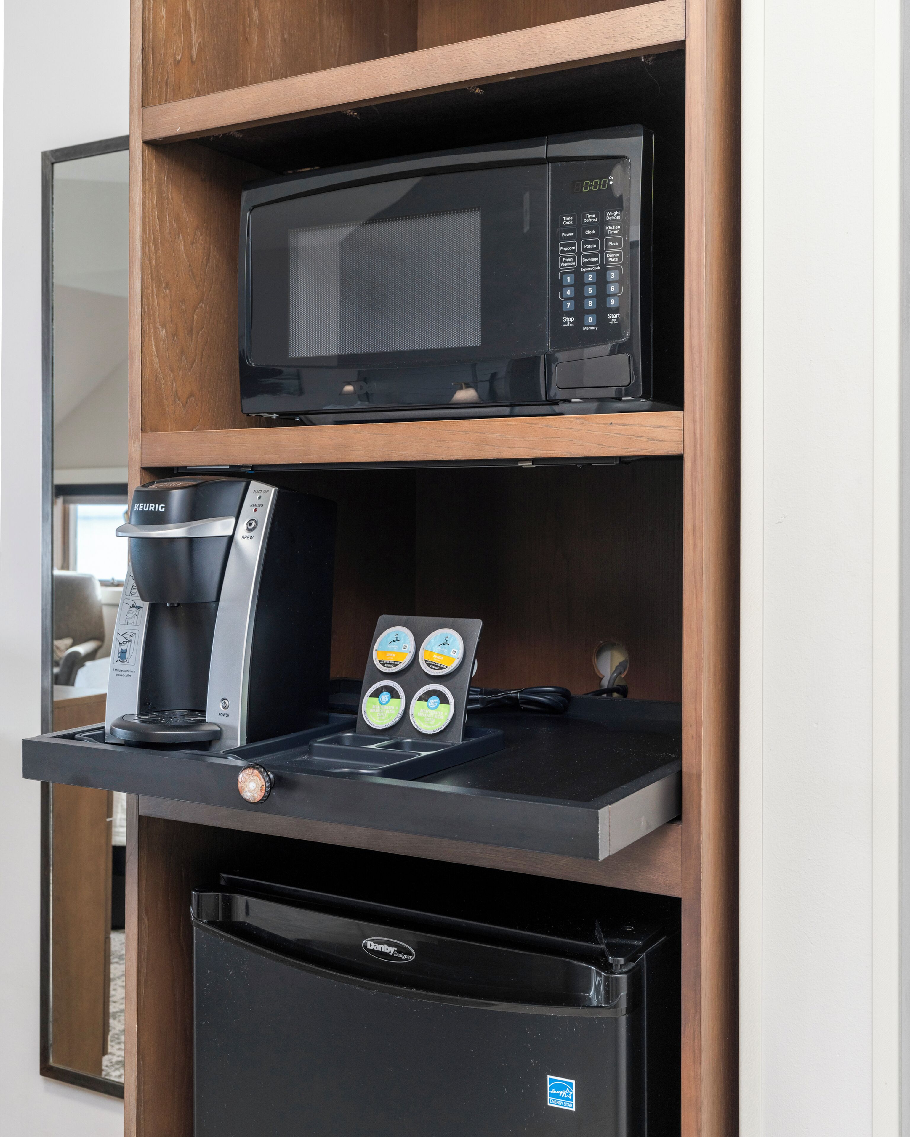 A kitchenette with a Keurig coffee maker, a microwave, and a refrigerator.