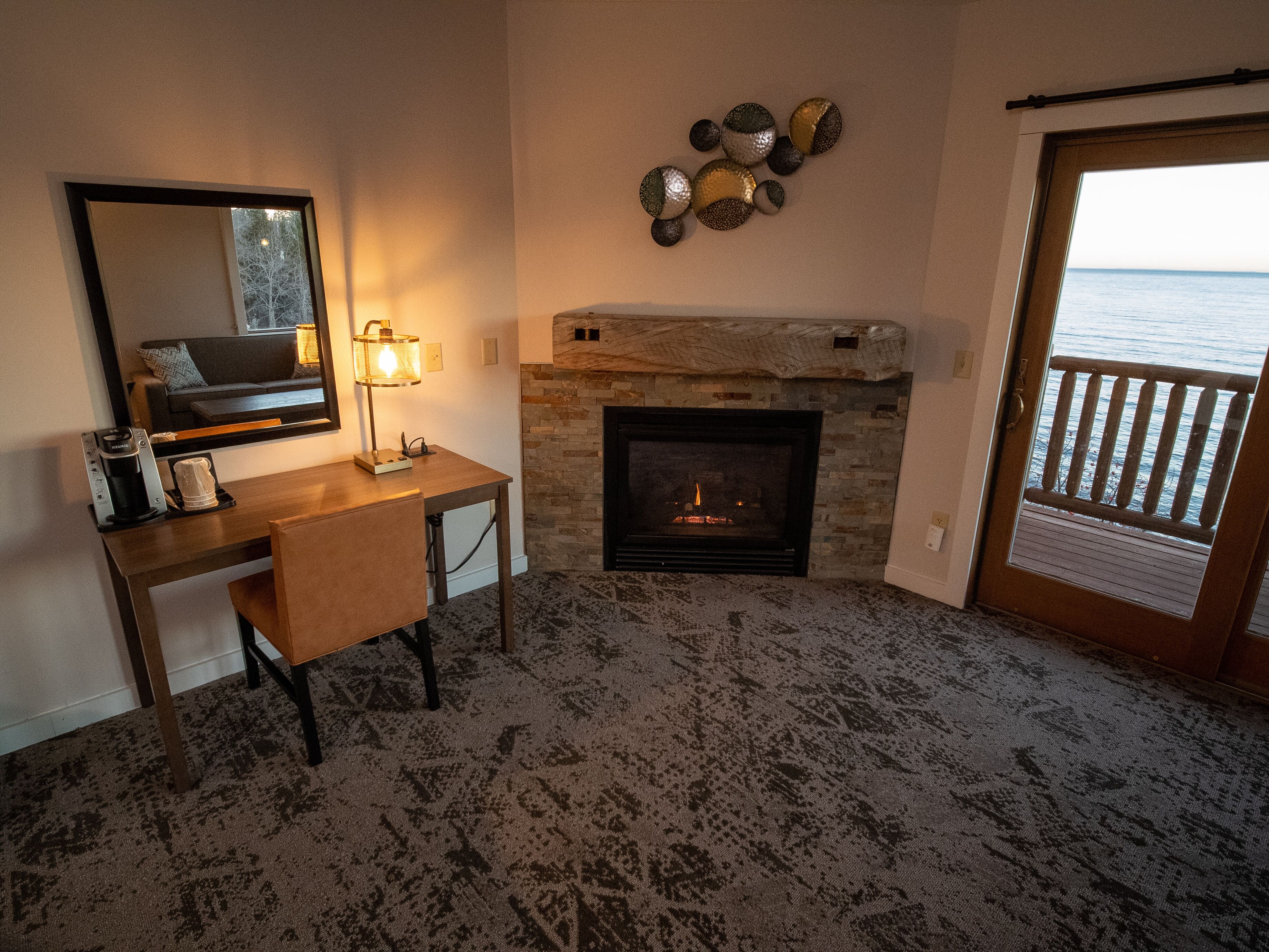 A cozy room with a fireplace, a desk, and a large mirror.
