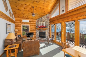 A log cabin interior with a stone fireplace, wooden furniture, and a television. - Grand Superior Lodge (Two Harbors)