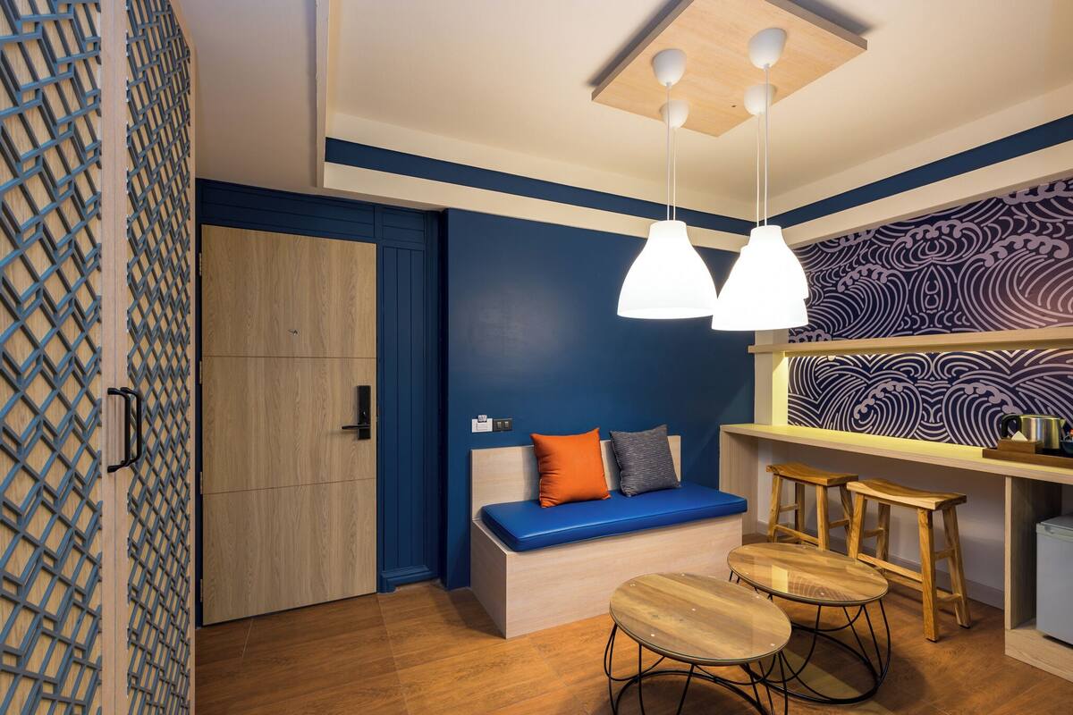 A modern room with a wooden bench, two hanging pendant lights, a patterned wall, and a small bar area.