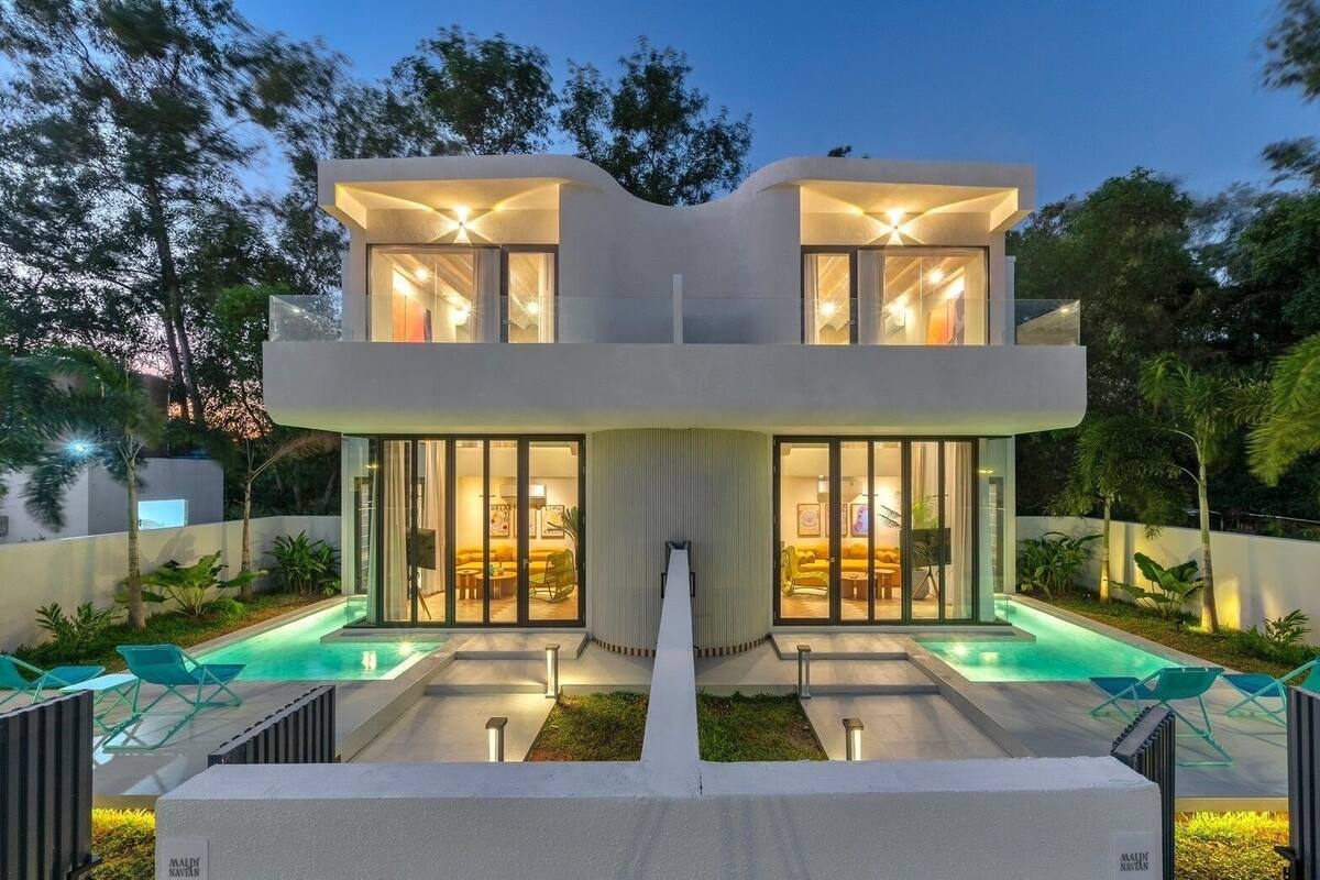 A modern two-story house with a swimming pool, large glass doors, and outdoor seating.