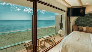 A room with a large window overlooking a beach, a bed, a television, and a cactus plant. - Maldives Beach Resort (Tha Mai)