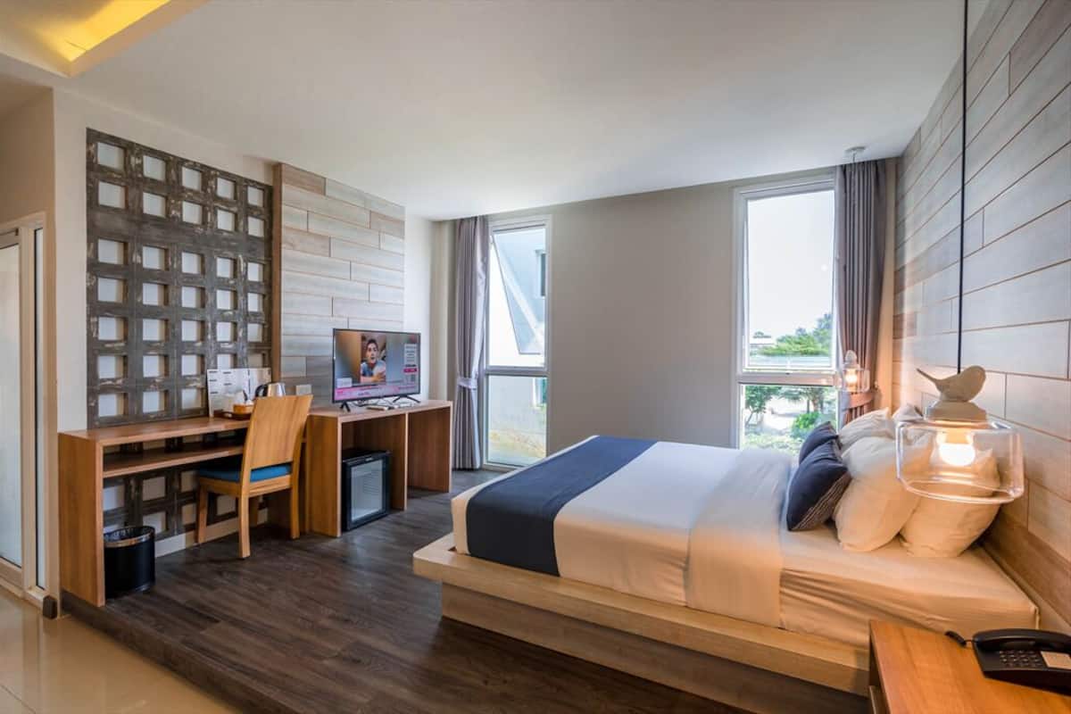 A modern hotel room with a bed, desk, and chair.