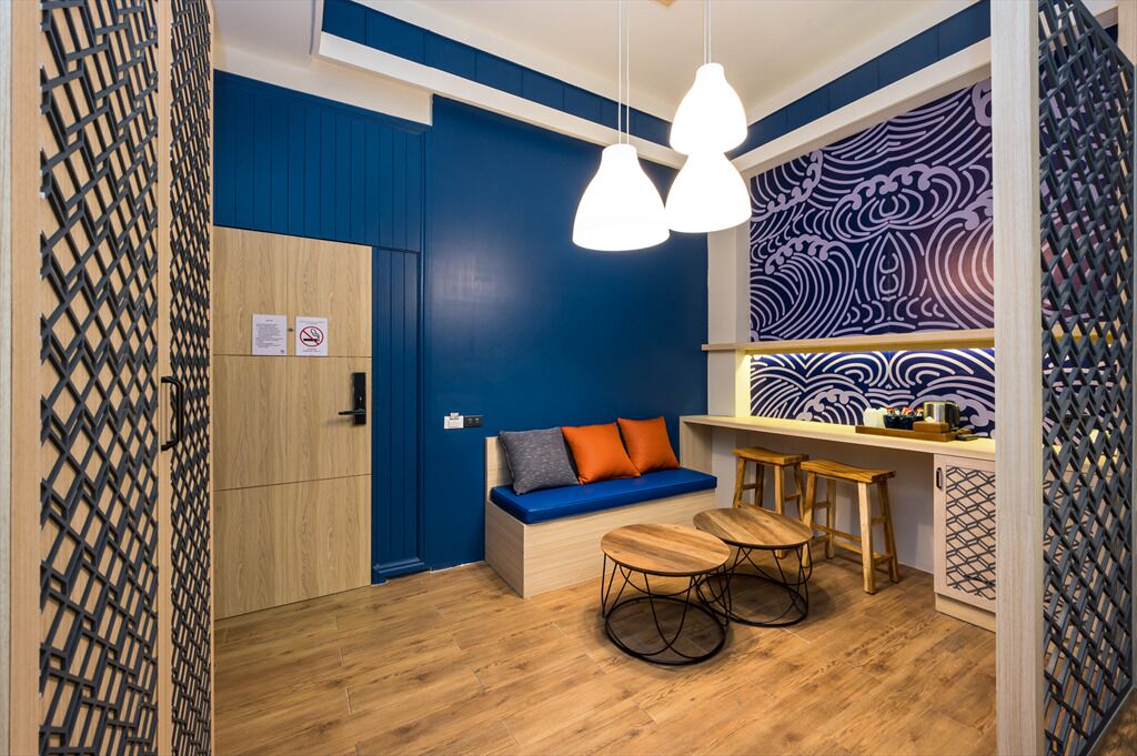 A compact room with a blue wall, a wooden bench, a small table, and hanging pendant lights.