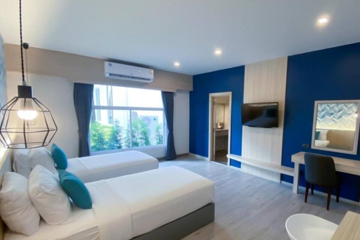 A modern hotel room with two beds, a desk, and a TV.