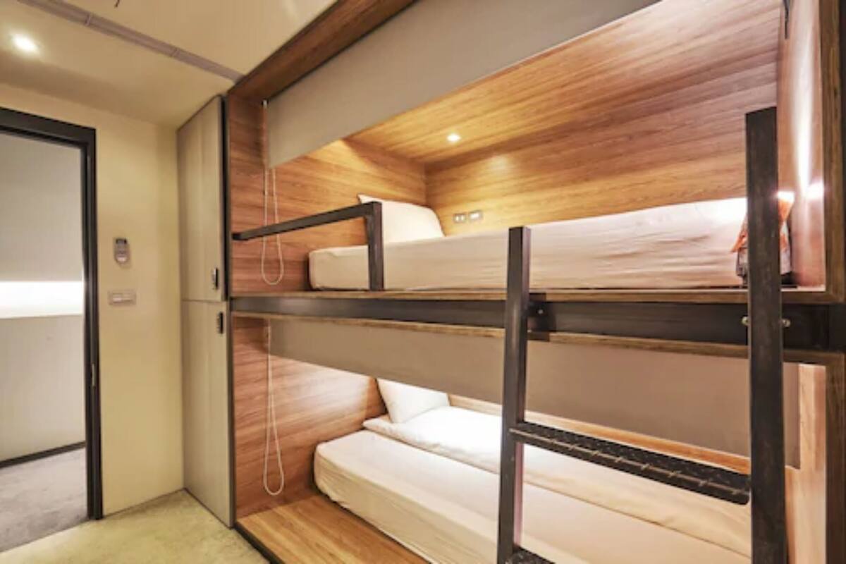 A bunk bed room with wooden paneling and a carpeted floor.
